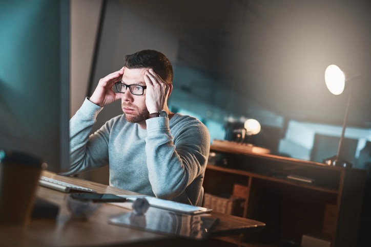 Shot of a mature businessman looking stressed out while working late on a computer in an office