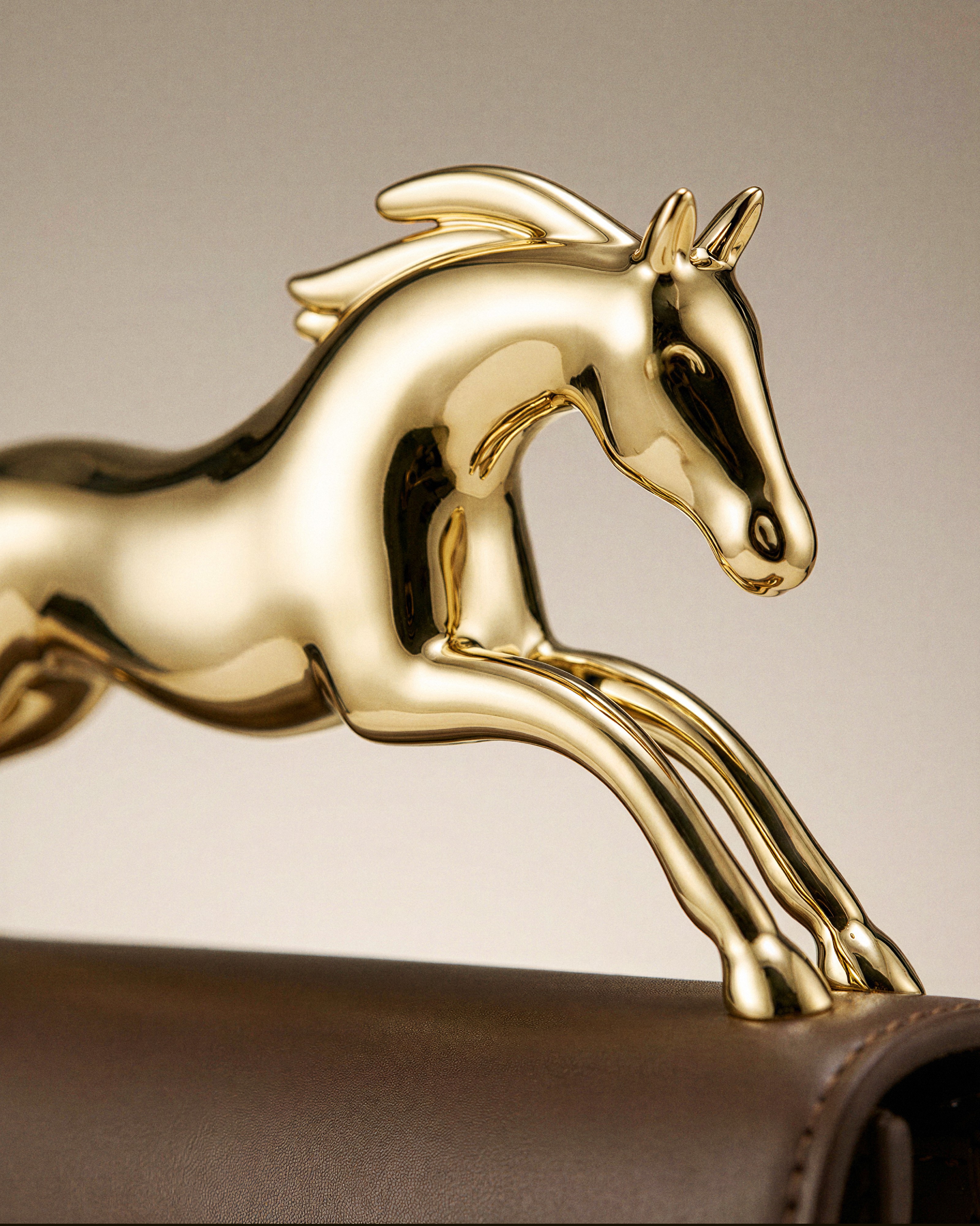 Gold horse figure on the clasp of a leather handbag