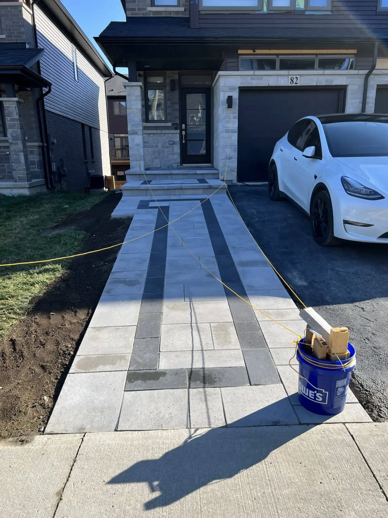 Freshly poured and patterned concrete driveway with a sleek, geometric design in front of a modern home.