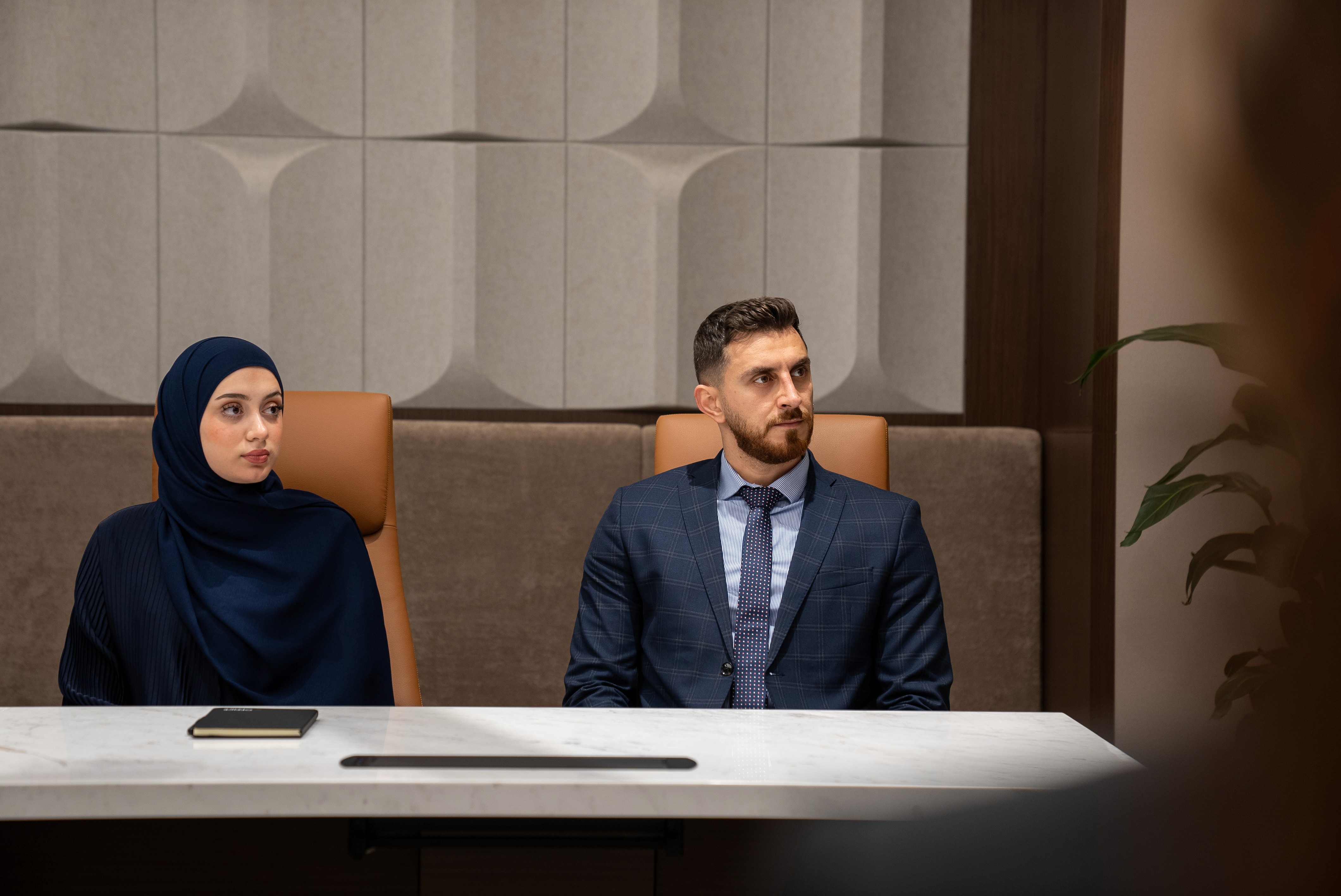 Two professionals seated in a soundproof meeting room.