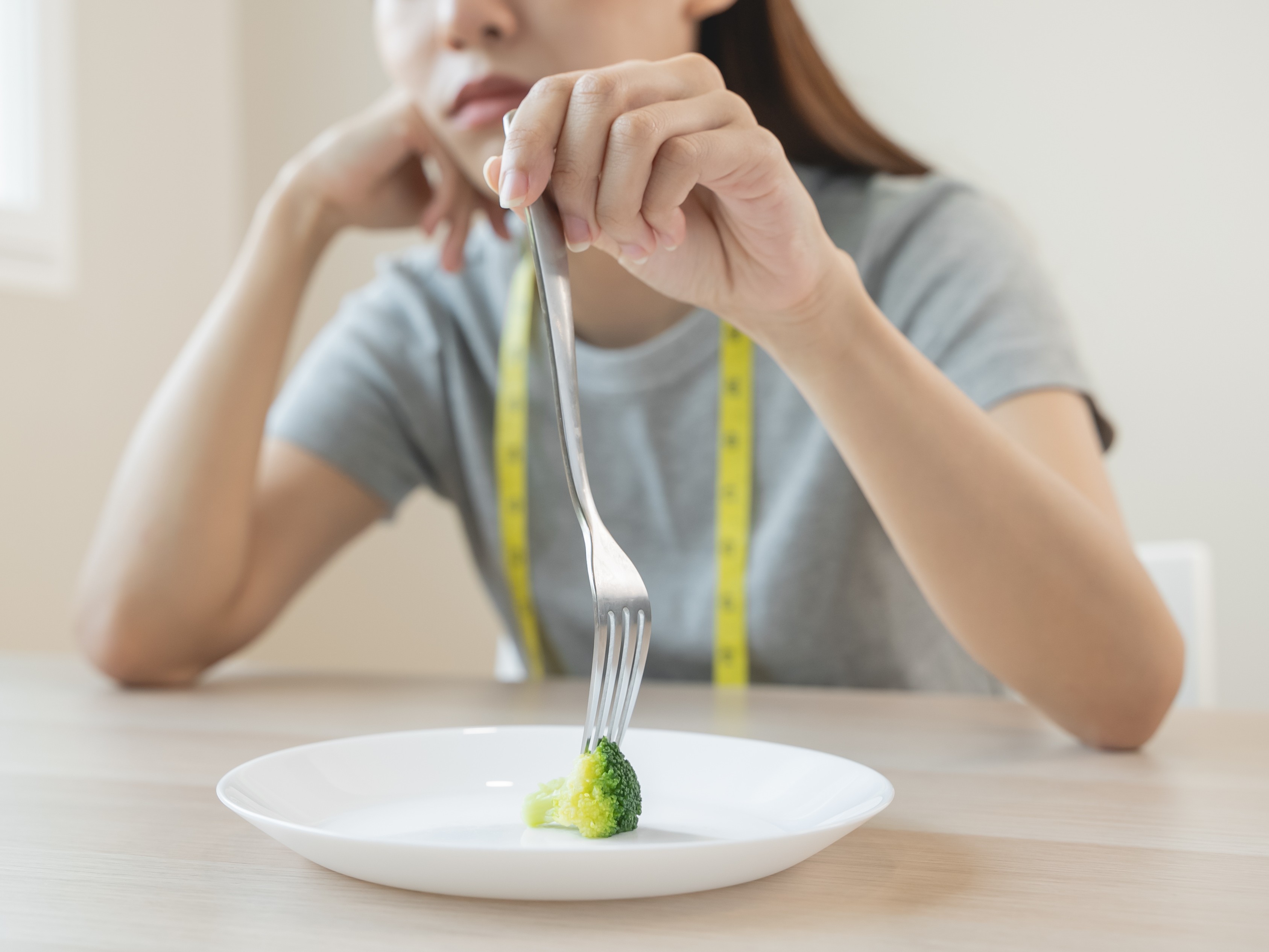 unhappy woman with broccoli on her plate feeling tired because she is being too restrictive with the fastest way to lose weight without exercising