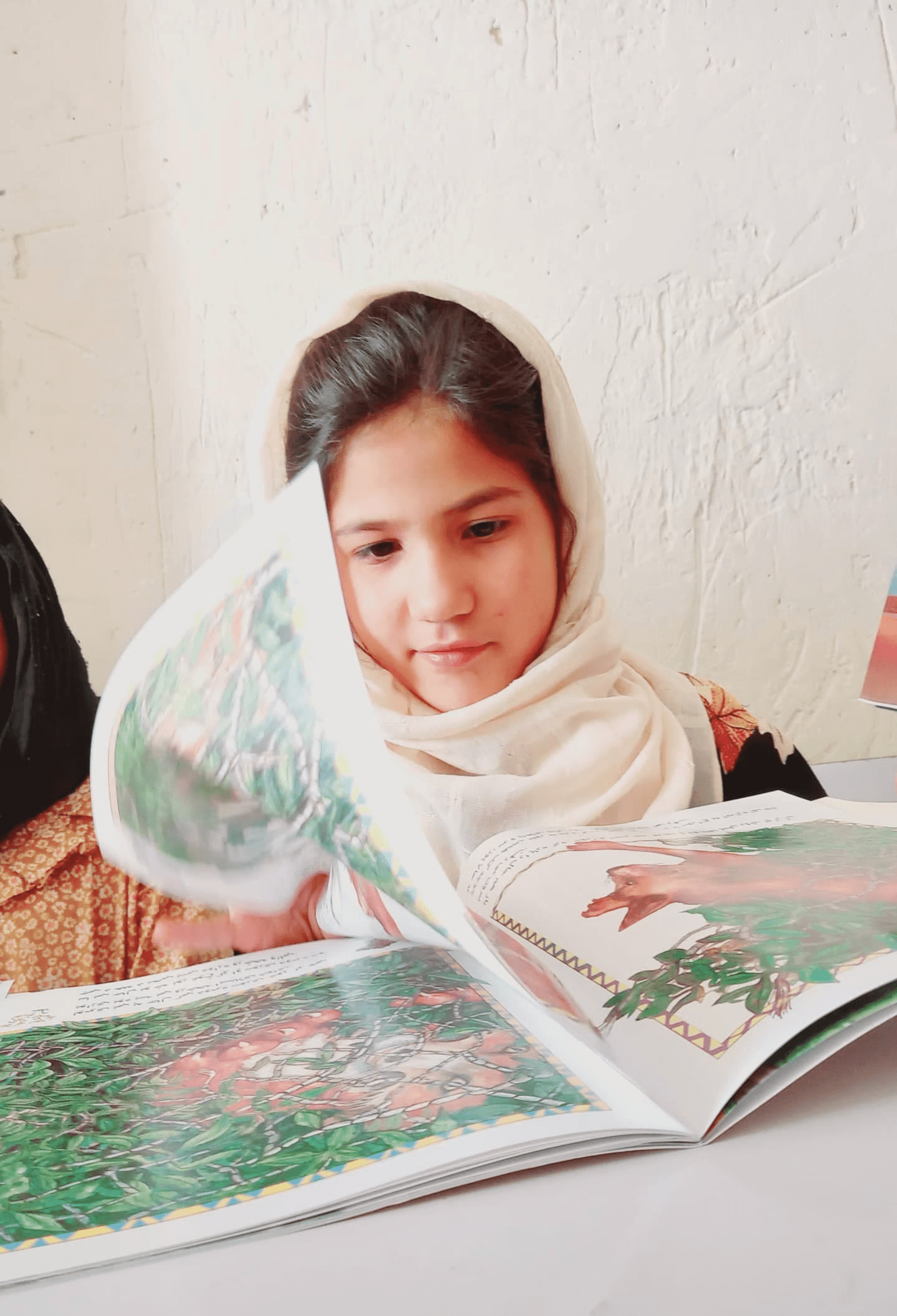 Girl in a headscarf reading a picture book