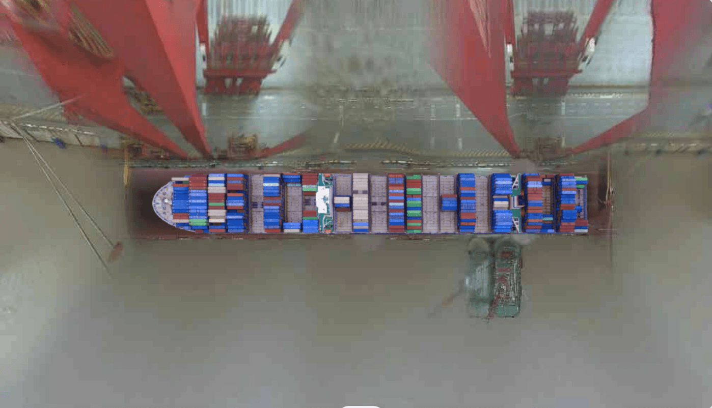 A smiling woman with her arms crossed, standing against a dark green background. She has long, dark hair.