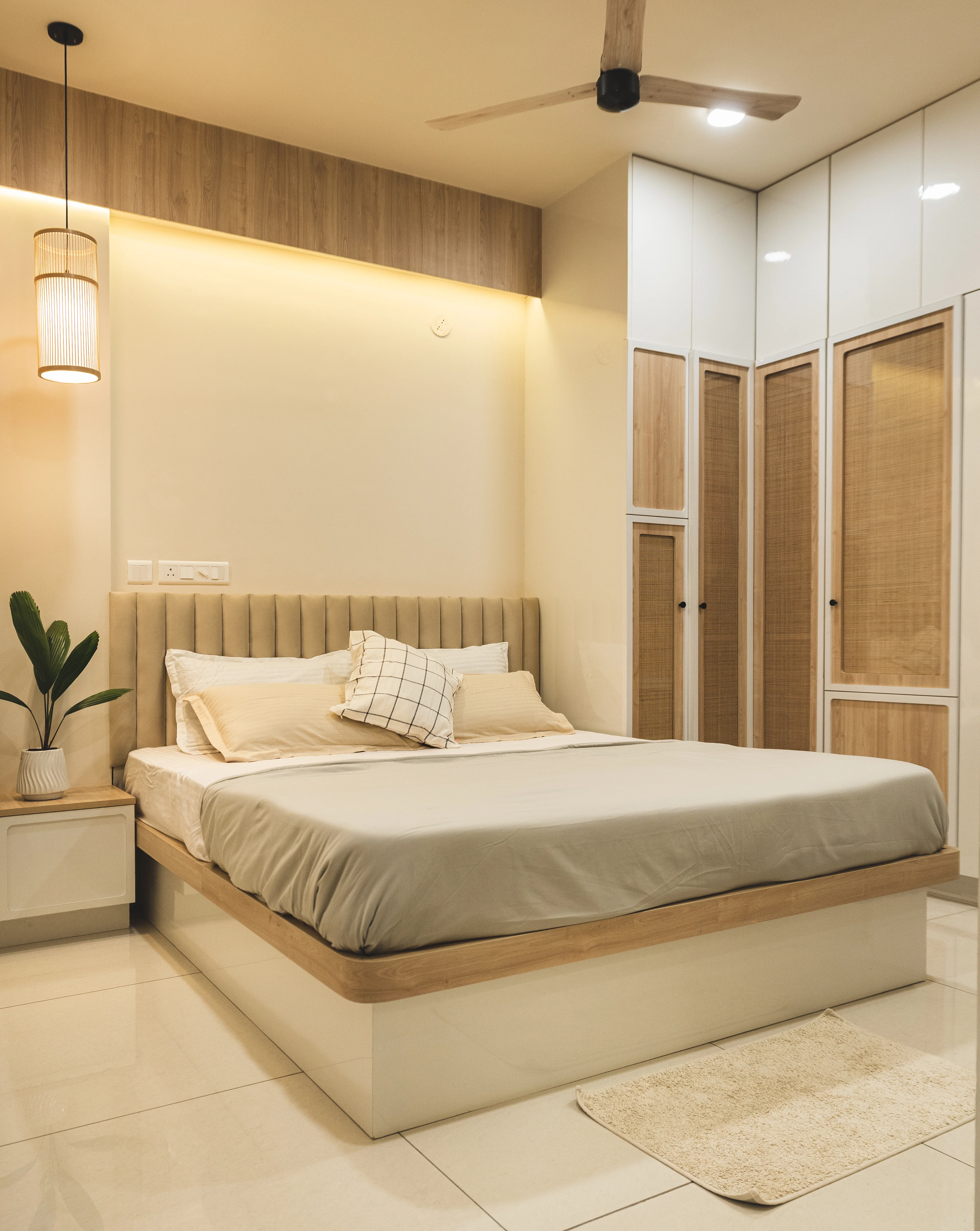 A stylish bedroom featuring a bed, dresser, and ceiling fan, designed with curves and minimal aesthetics for South Indian homes.