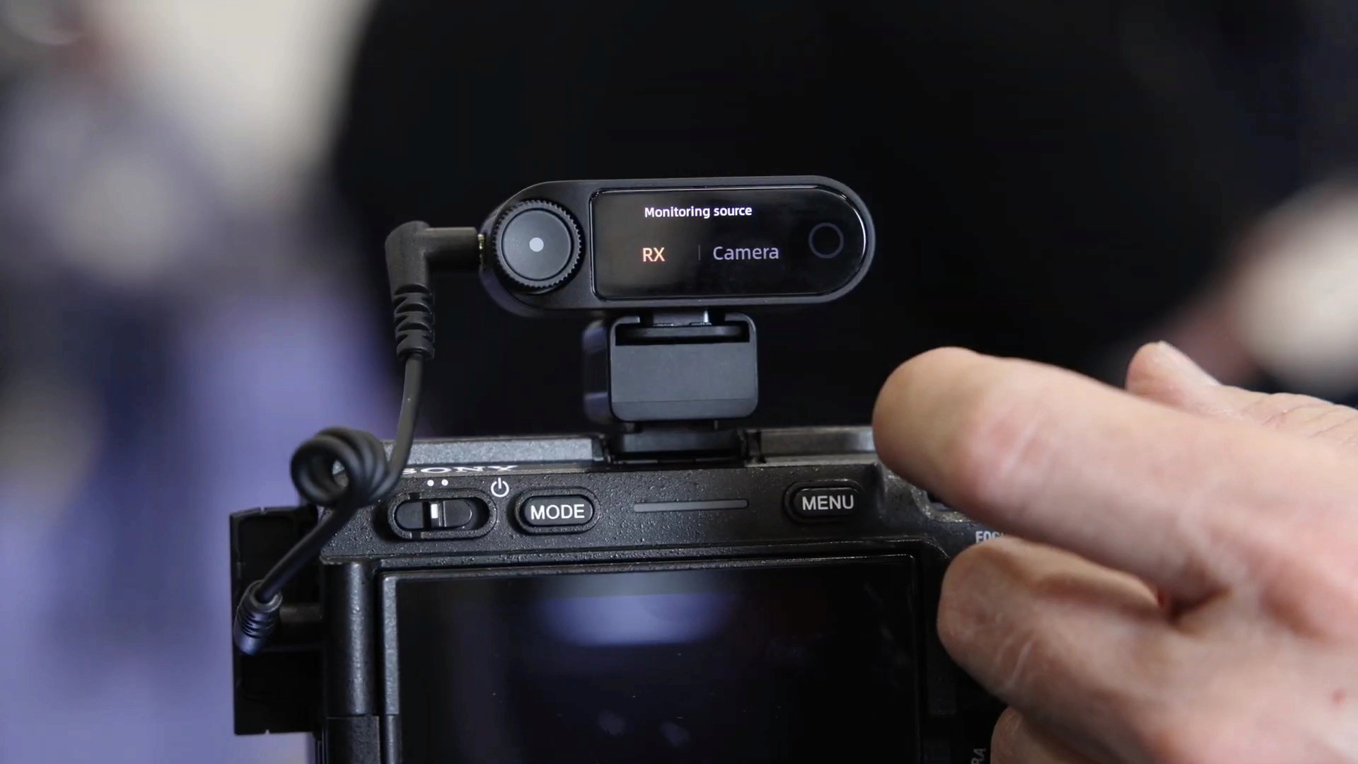 Close-up view of a wireless microphone receiver mounted onto the hot shoe of a digital camera.