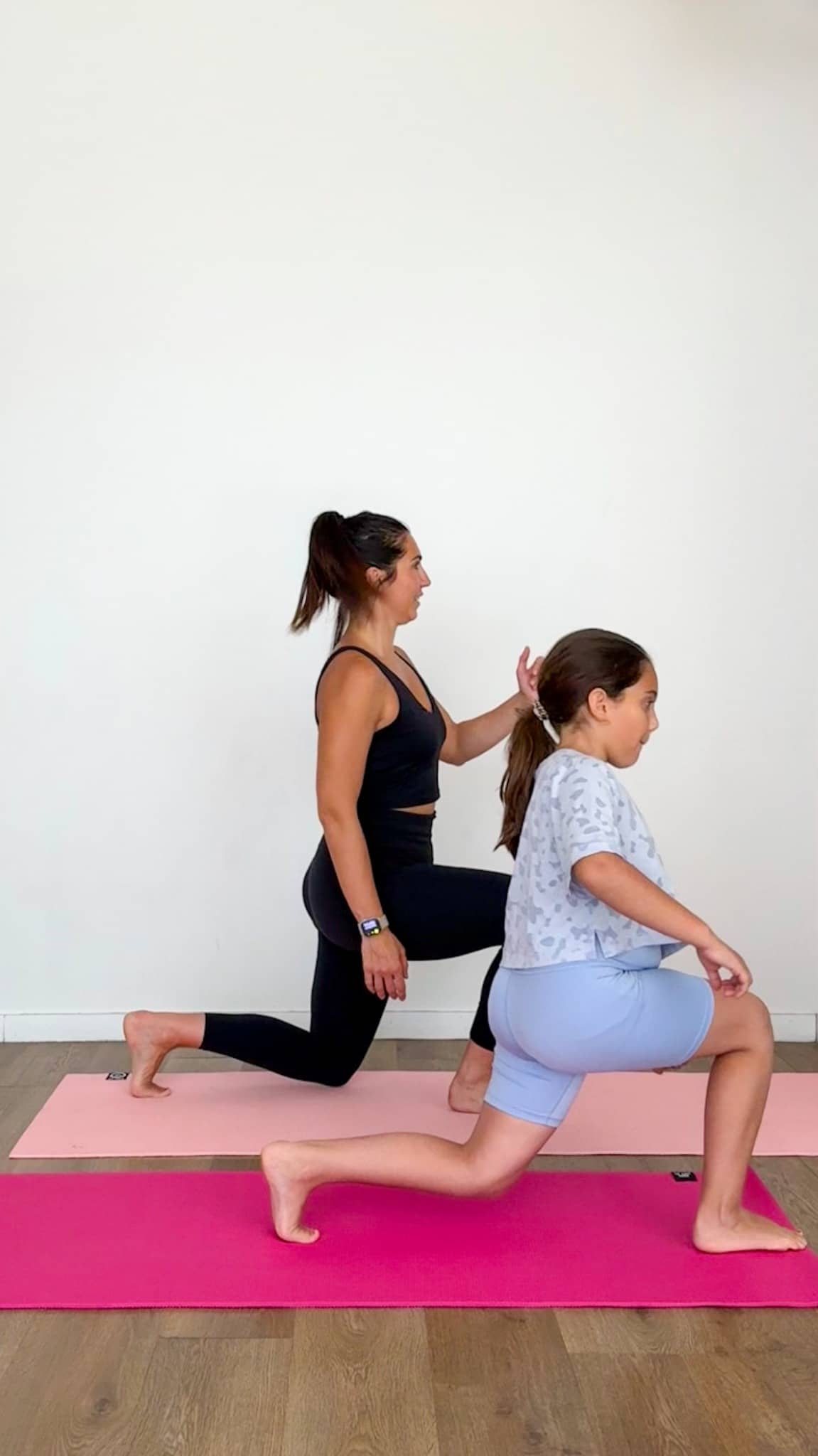 Une maman et sa fille réalisent des fentes sur des tapis pendant une séance de fitness en famille à la maison.