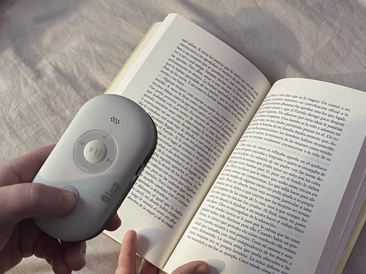 Una mano sujeta la Lupa Inteligente sobre un libro