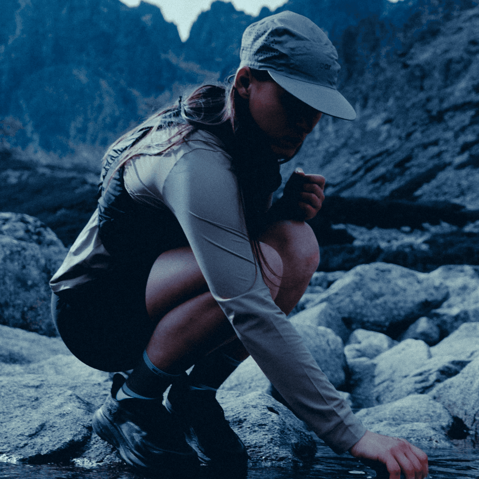 picture of a woman taking water from the stream.