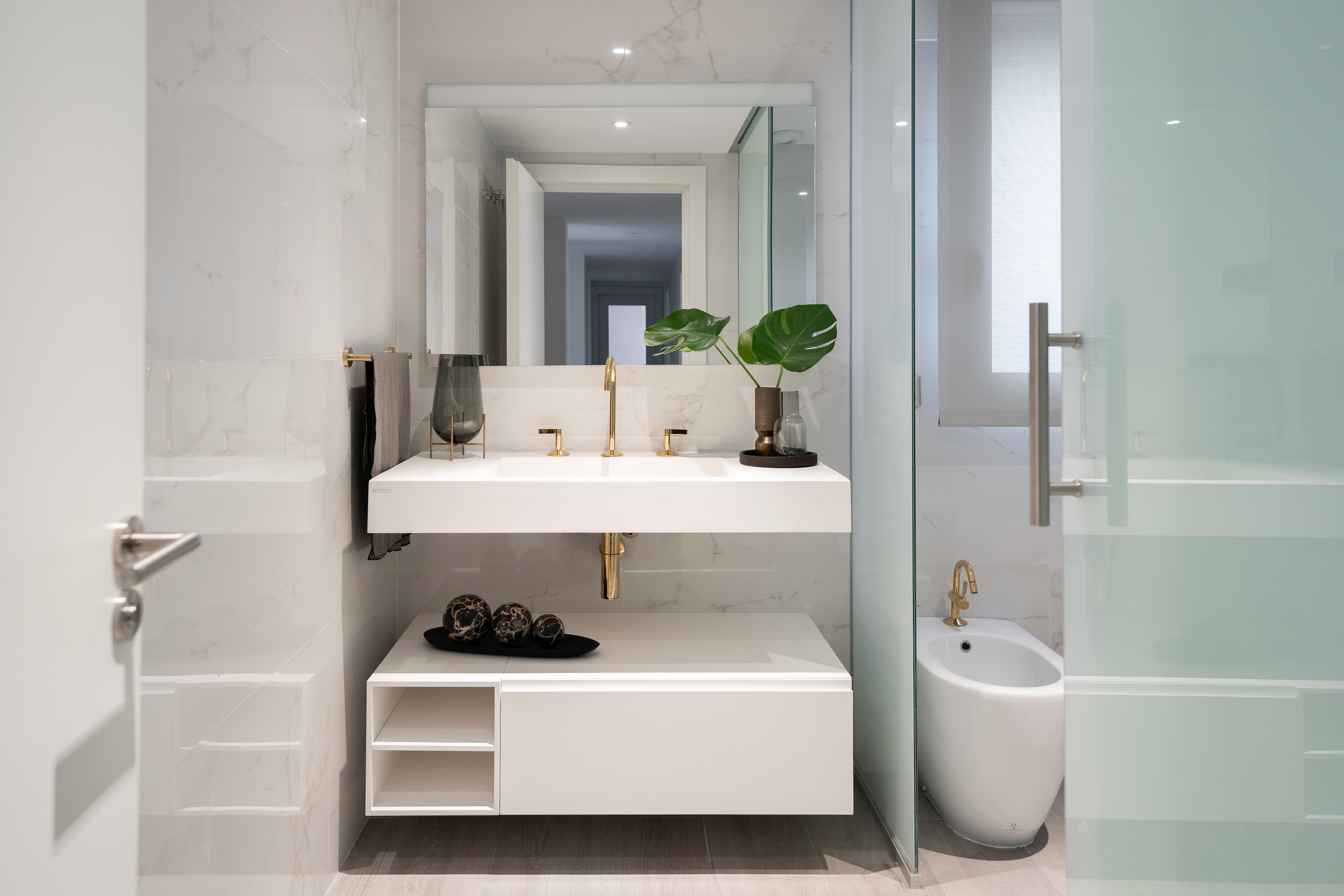 Baño con paredes de mármol blanco y mueble blanco
