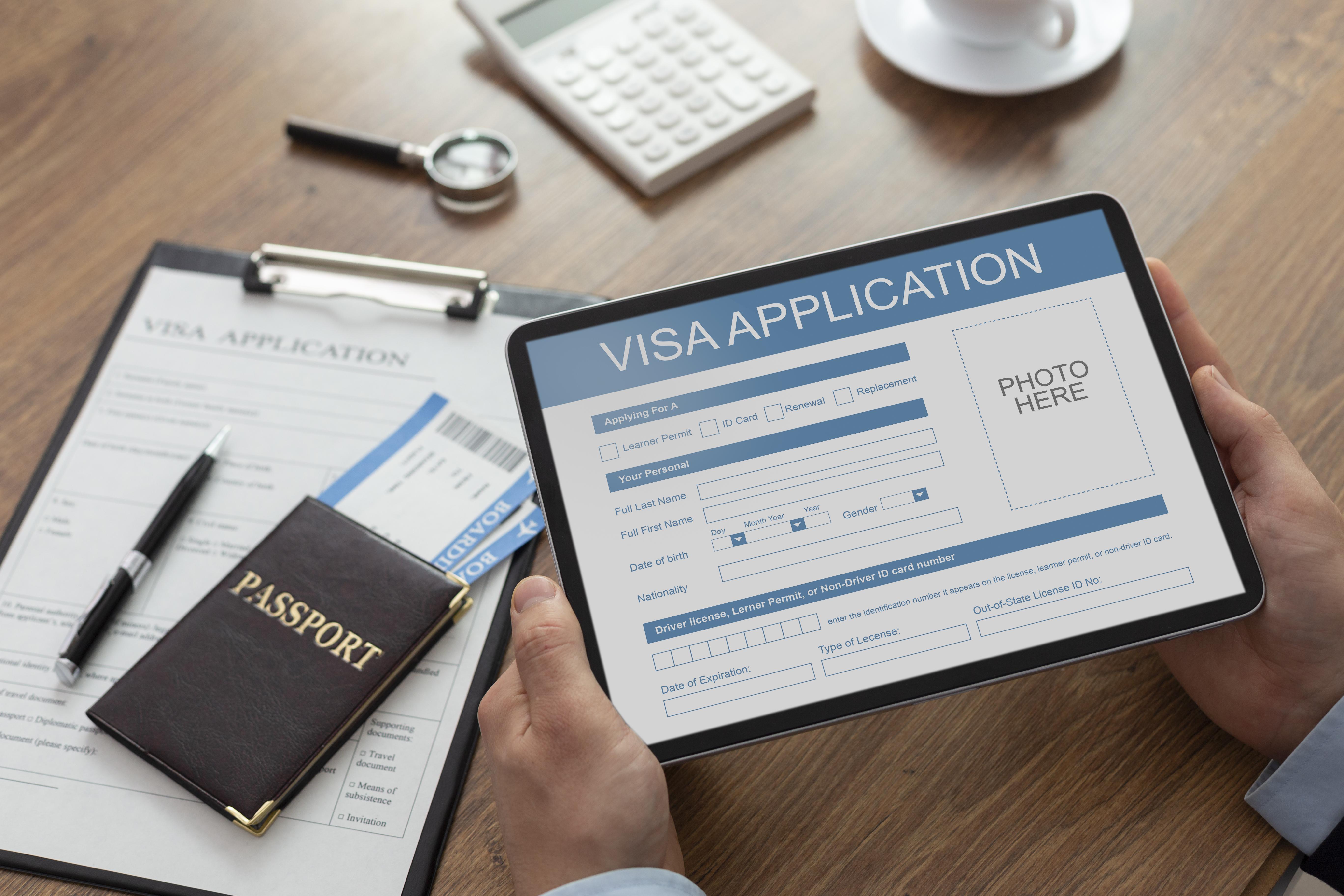 A close up photo of hands holding a tablet, with the screen showing a visa application form. 