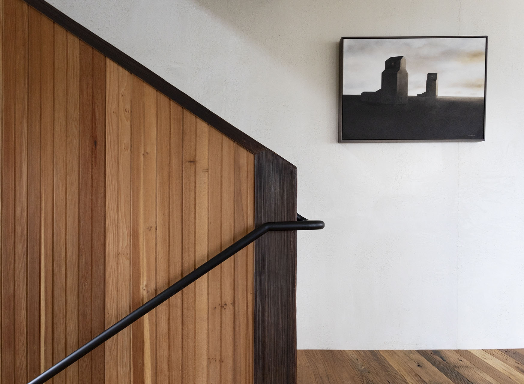 木條扶手樓梯旁掛著黑白抽象畫作，牆面材質與畫面構成視覺層次對比