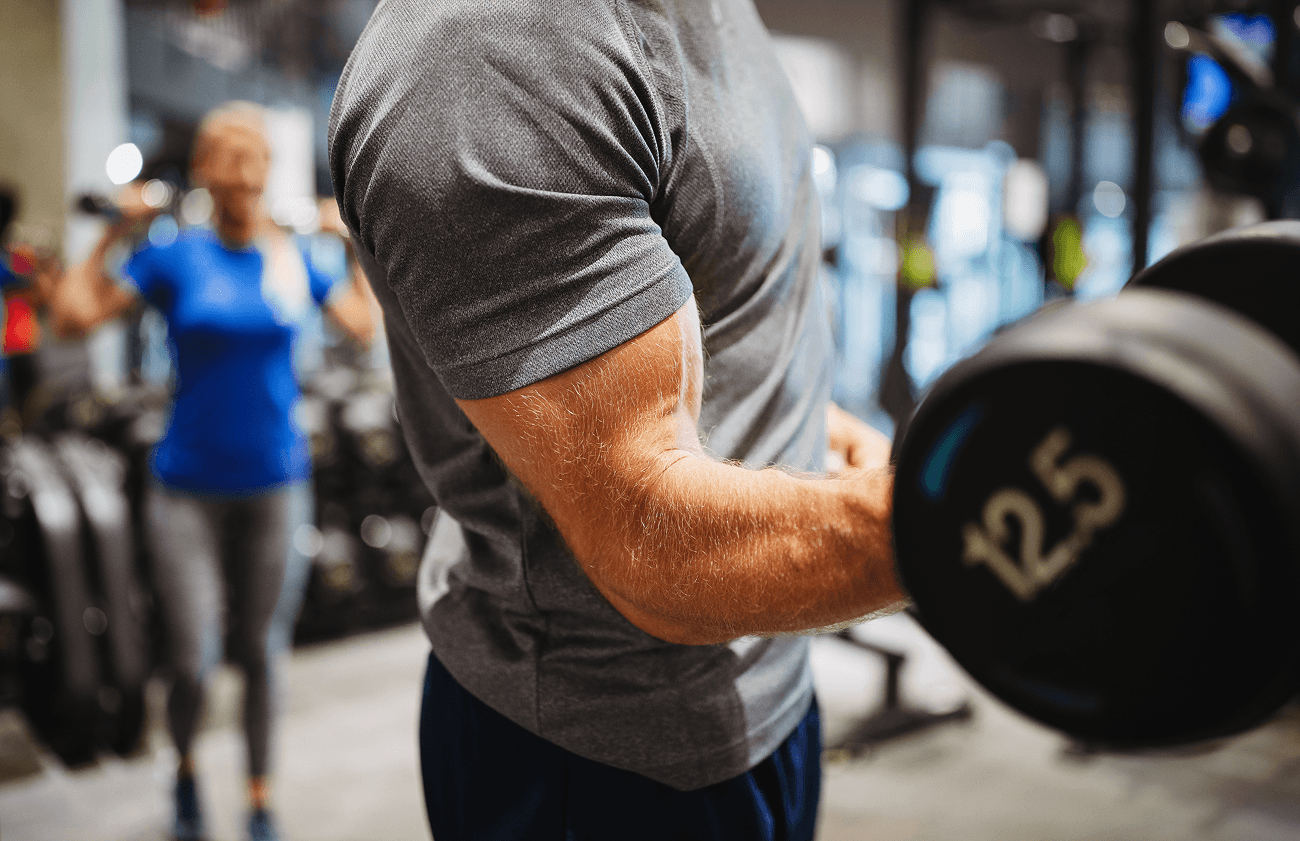 Close-up of a man curling a dumbbell in a gym