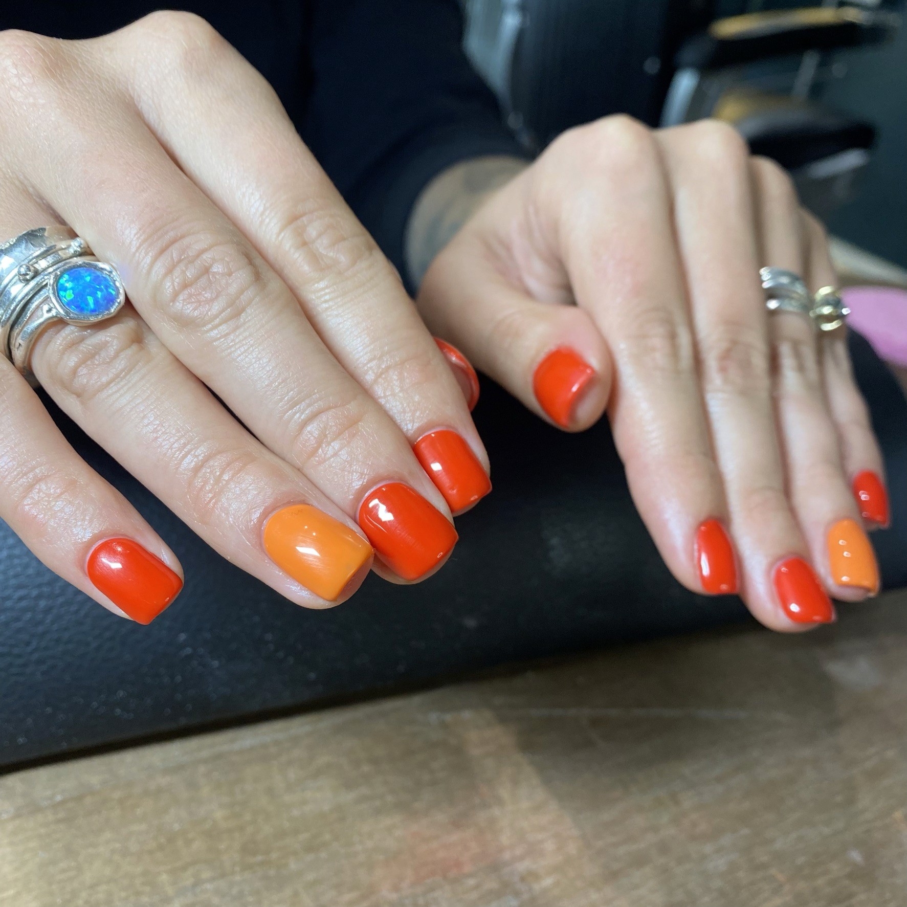 Short, square-rounded nails in a simple but bold palette of glossy pumpkin orange and vibrant tomato red.