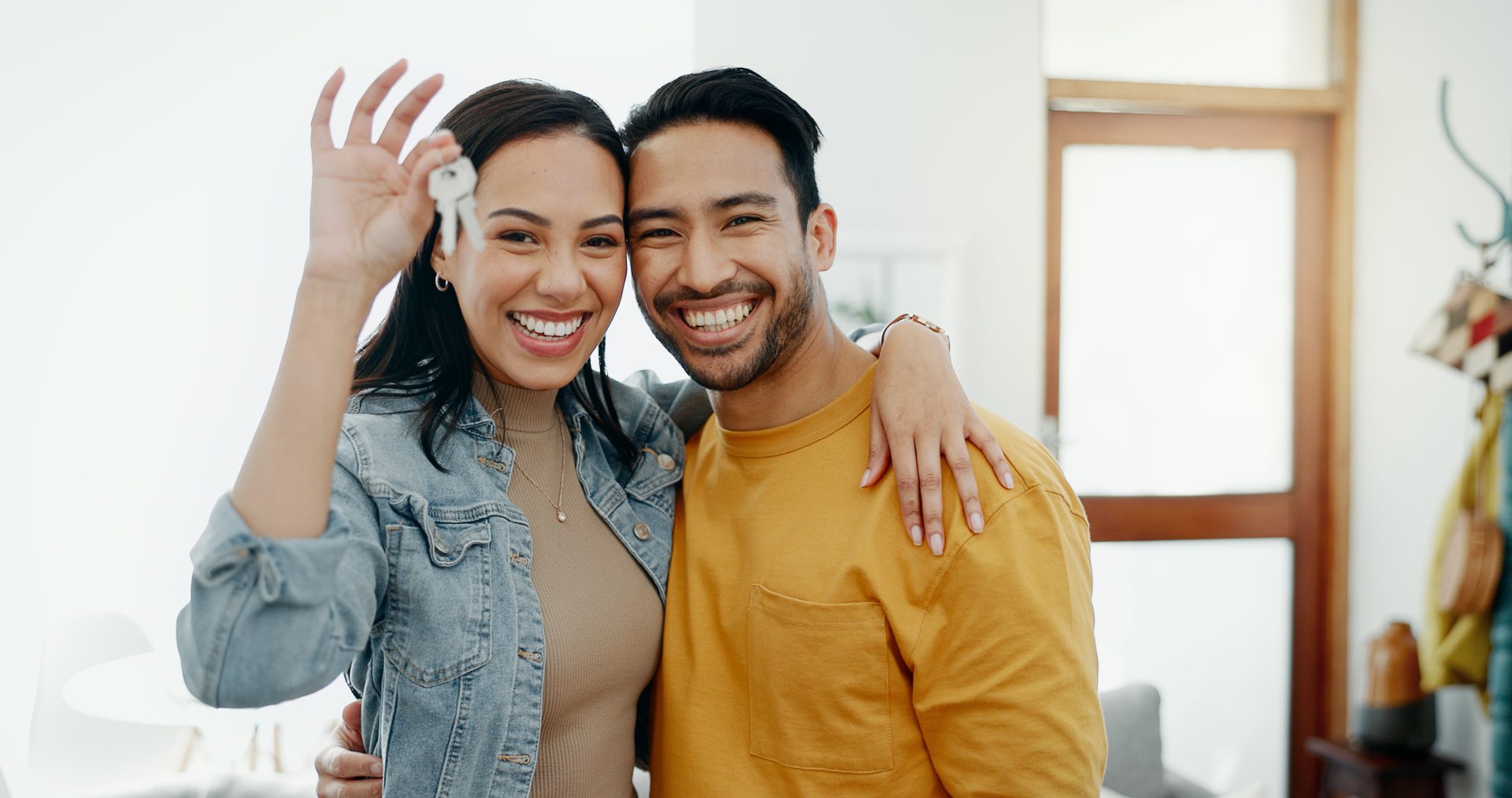 Couple with keys to new home, smiling broadly.