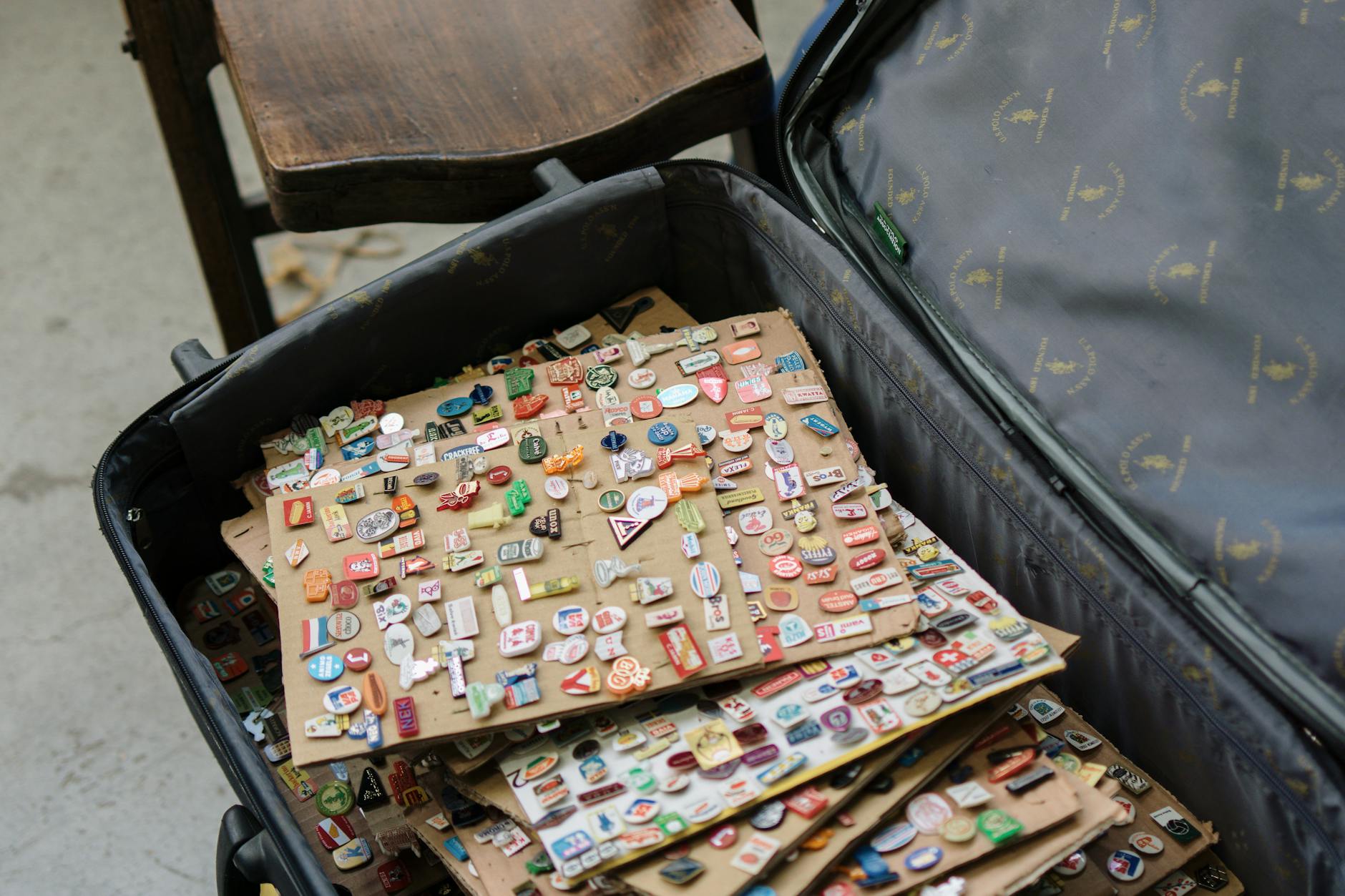 A suitcase full of vintage enamel pins, showcasing various designs and colors, ideal for collectors.