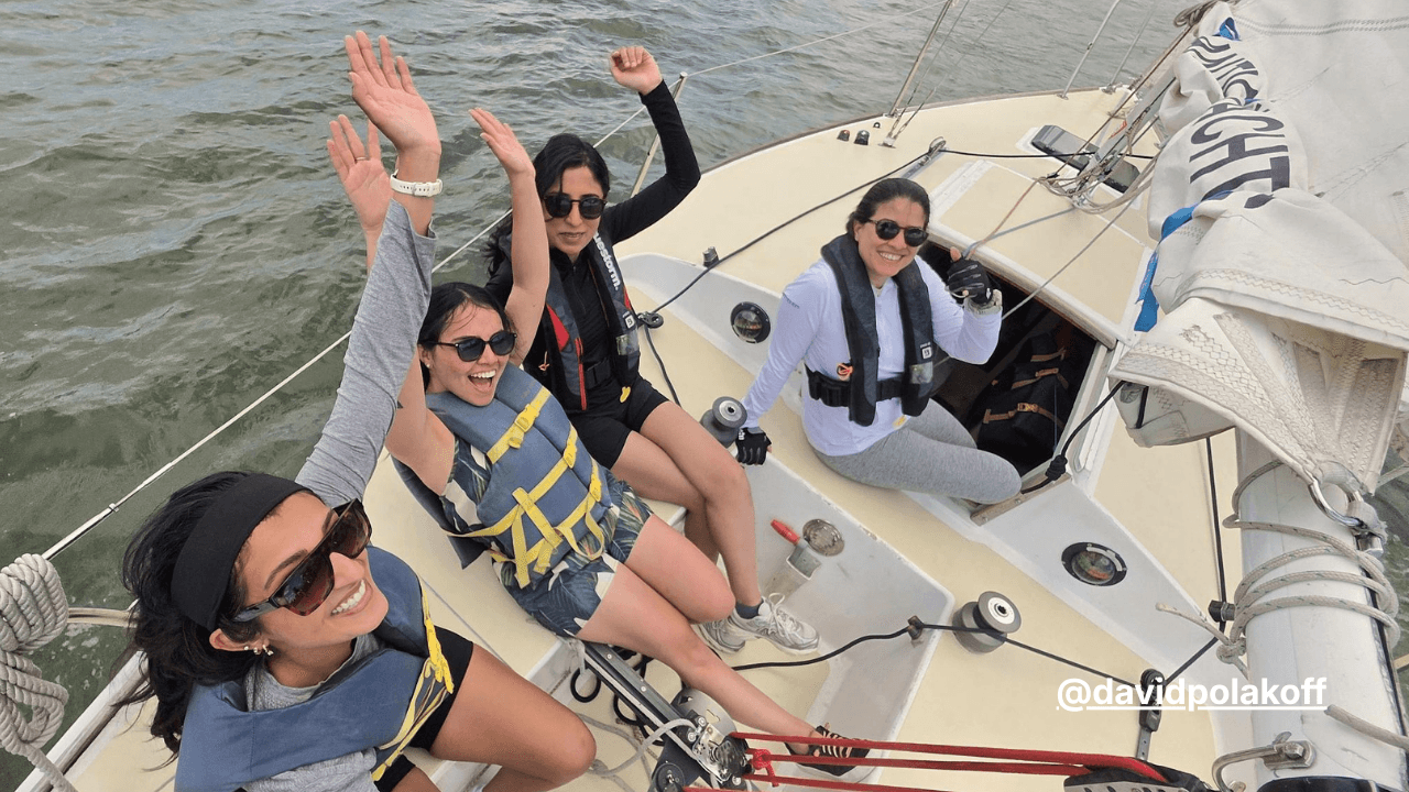 Students smiling aboard a sailboat during a hands-on sailing lesson, highlighting the community and experience-building that continue beyond certification.