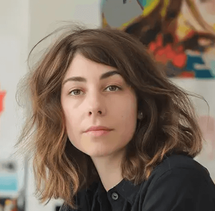Sara Lindqvist, freelance designer, sitting at her desk in a colorful art studio