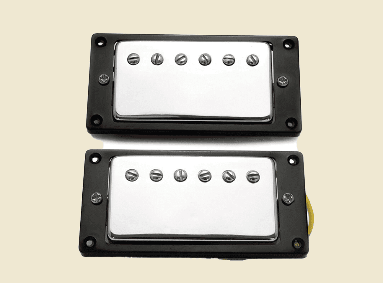 Two guitar pickups with black frames and chrome covers on a beige background
