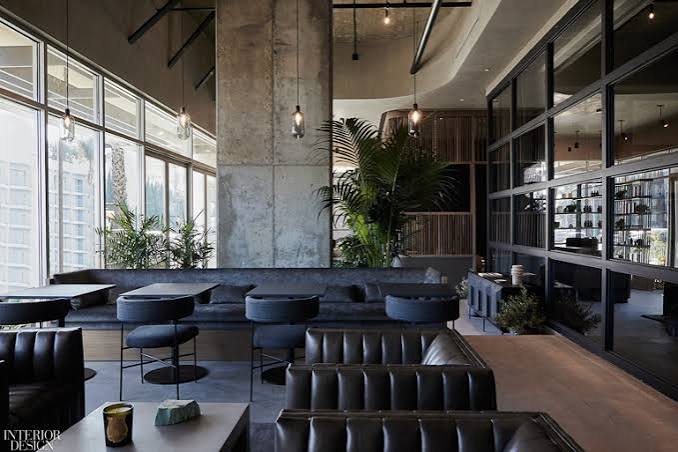 High-rise luxury fitness floor with dark walnut slatted ceiling, fluted column details, full-length city-view windows, and a curated mix of strength and cardio equipment