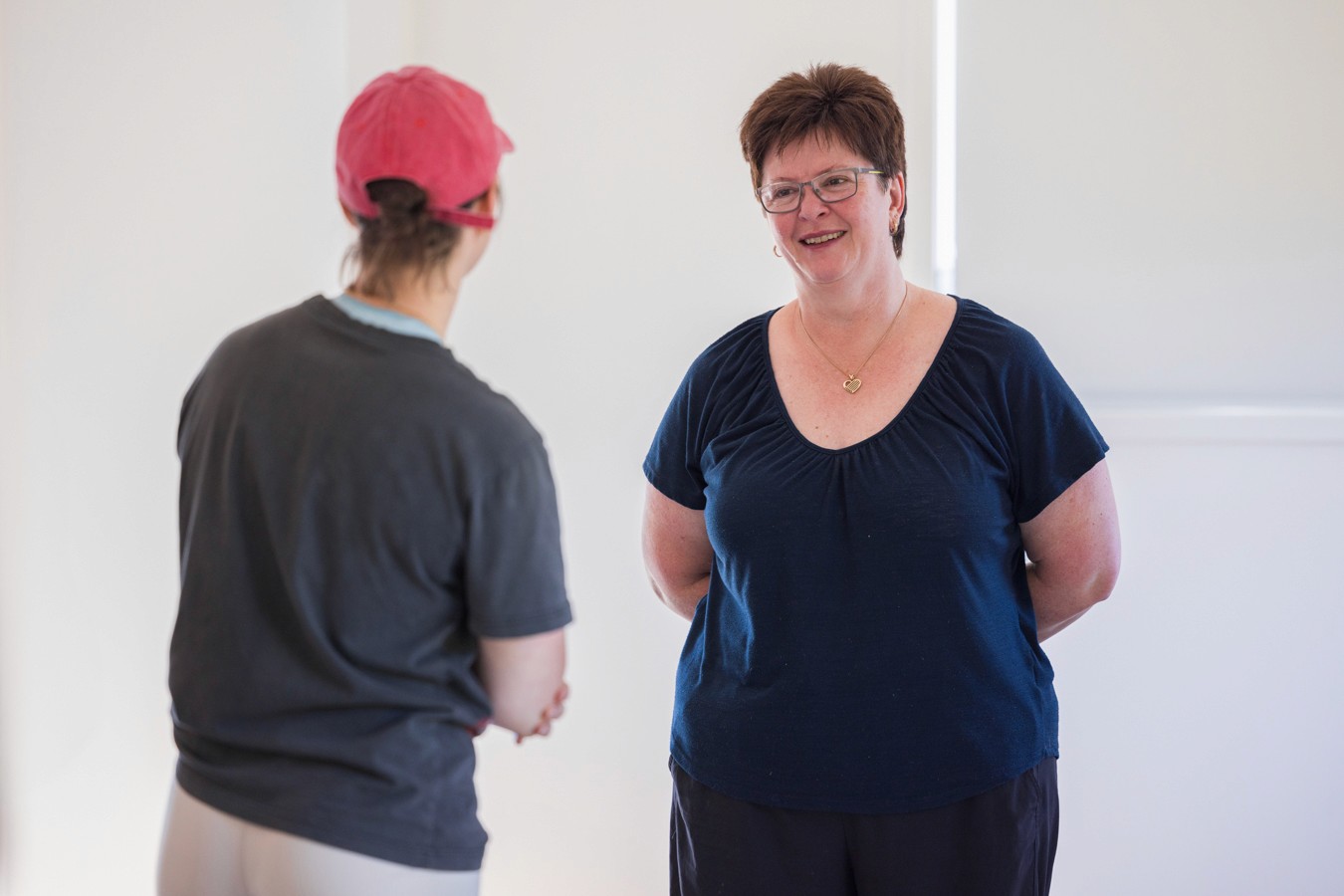 Two women standing opposite each other smiling