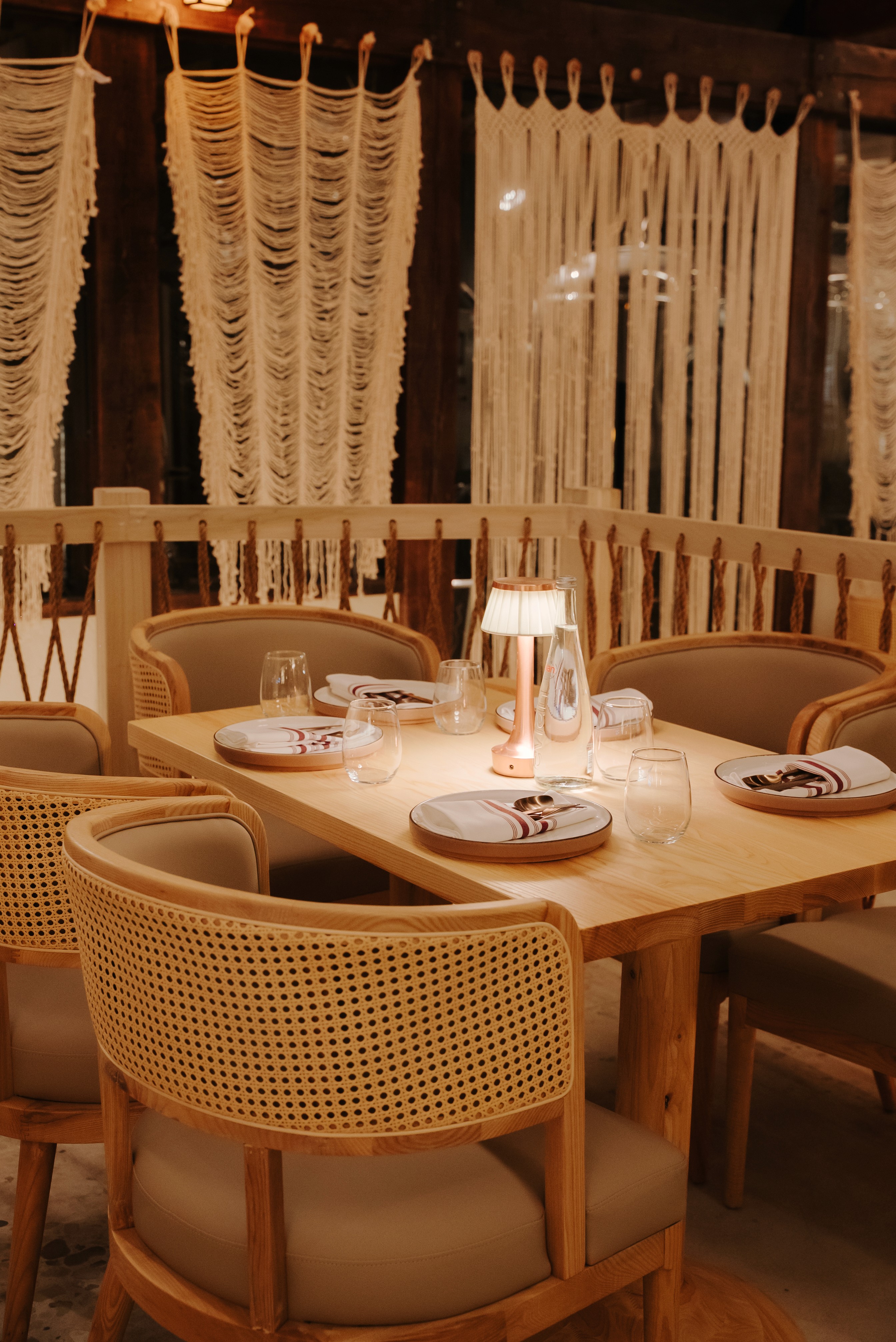 Elegant table setting at Dhoom Toronto with natural wood furniture, soft lighting, and a refined modern Indian dining ambiance.