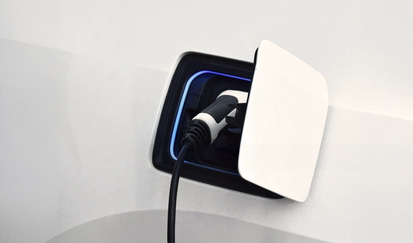 A close-up of an electric vehicle charging station with a connector partially revealed.