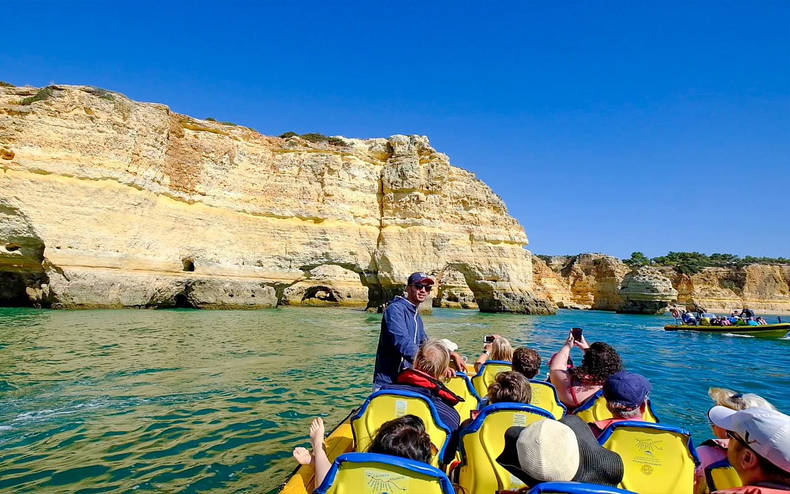 Tourists on a boat near Algarve cliffs during a 2-hour dolphin watching and cave cruise.