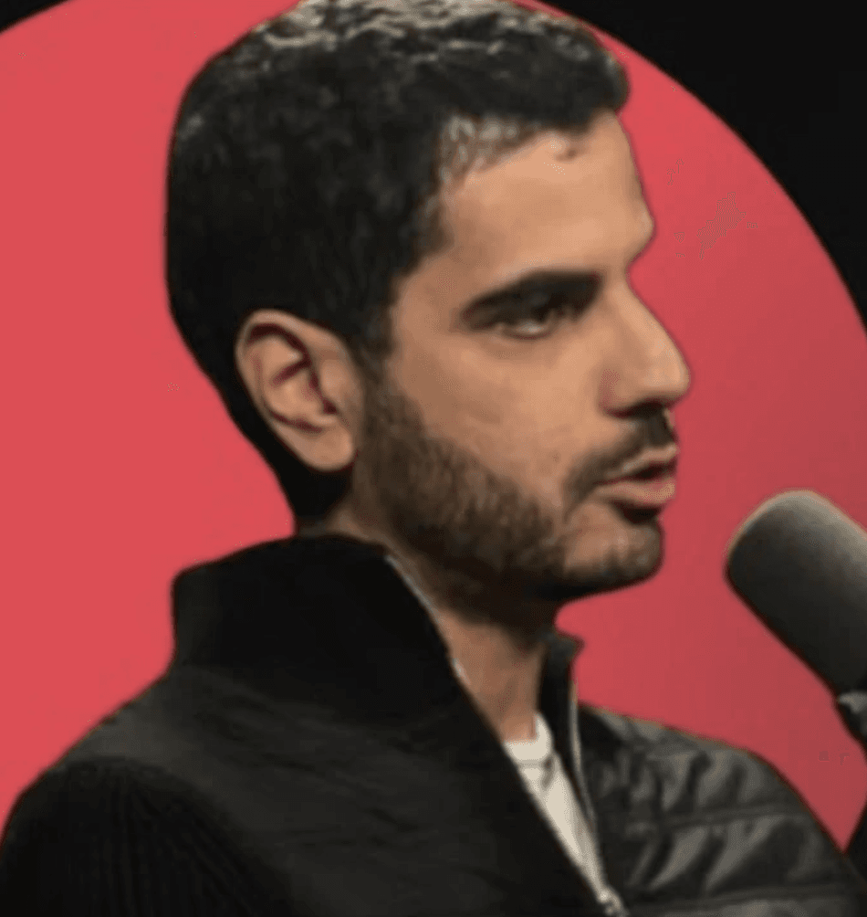 A man wearing glasses and a suit jacket, looking confidently at the camera.