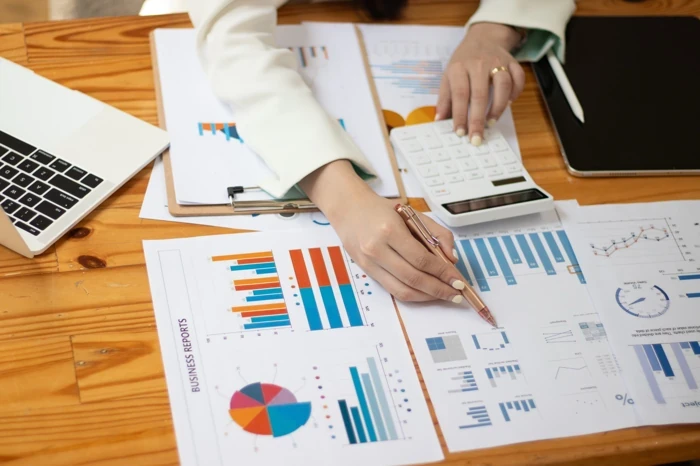Donna analizza dati finanziari con grafici e calcolatrice su scrivania