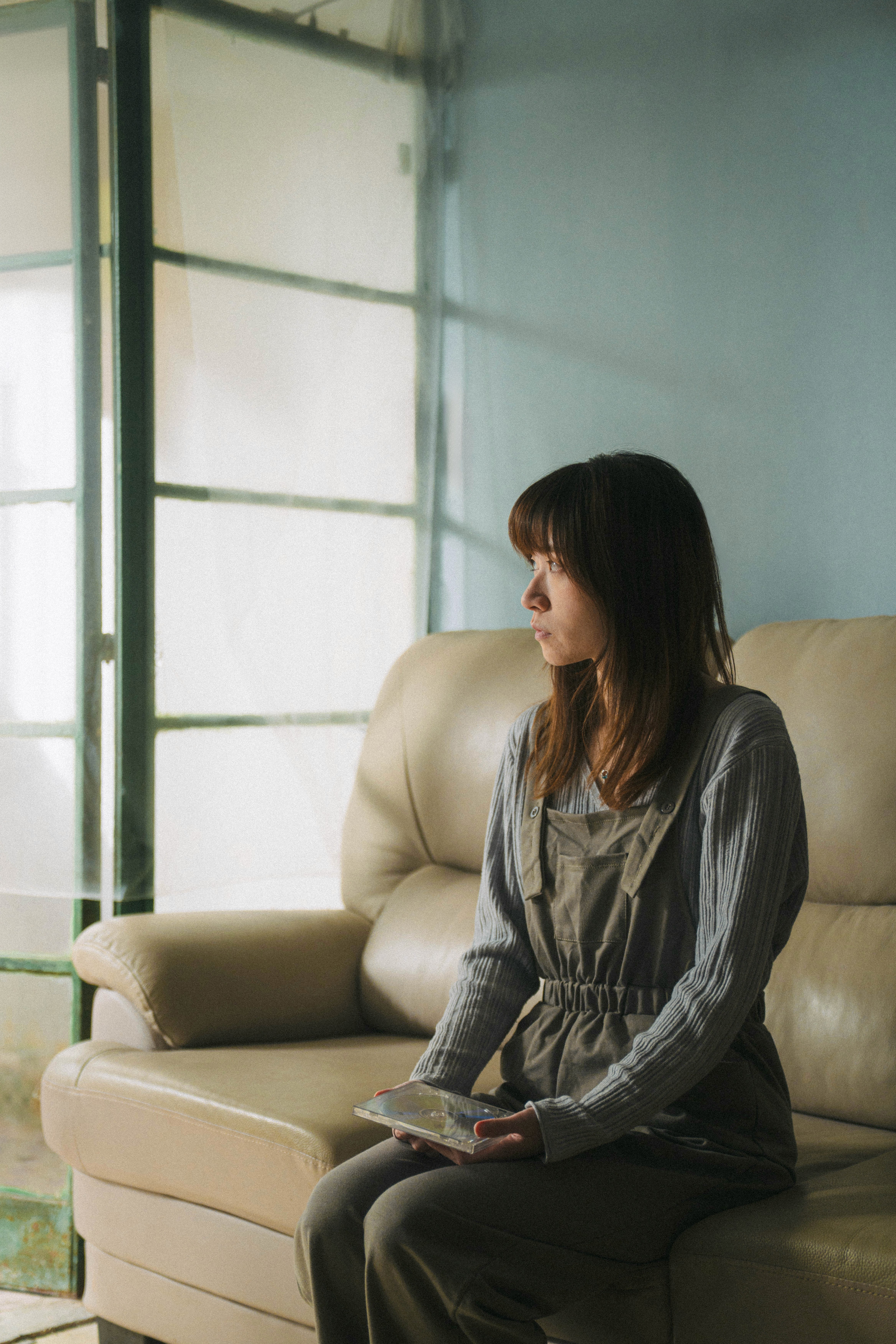 Alice in adulthood looking outside the window holding the gift from her dead mother
