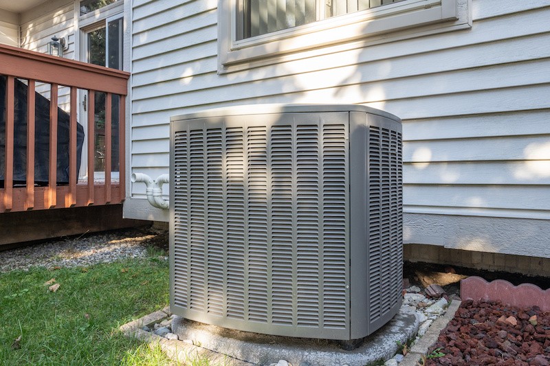 A hand adjusts a modern smart thermostat mounted on a wall. The black circular display shows the temperature set to 78 degrees Fahrenheit with a green leaf icon below the number.