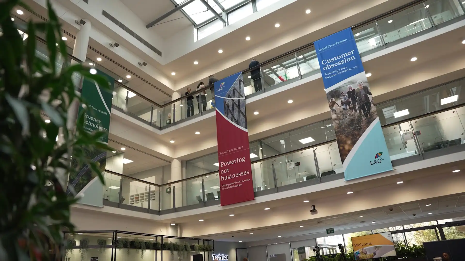 Interior atrium at the L&G Retail Tech Summit venue, featuring branded banners and wayfinding across multiple floors.