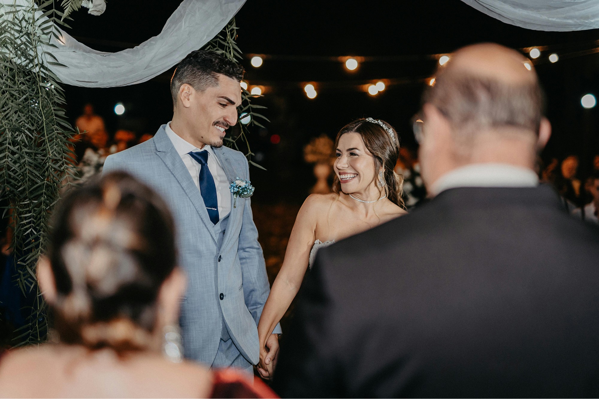 Bride and groom smiling at each other during an evening ceremony