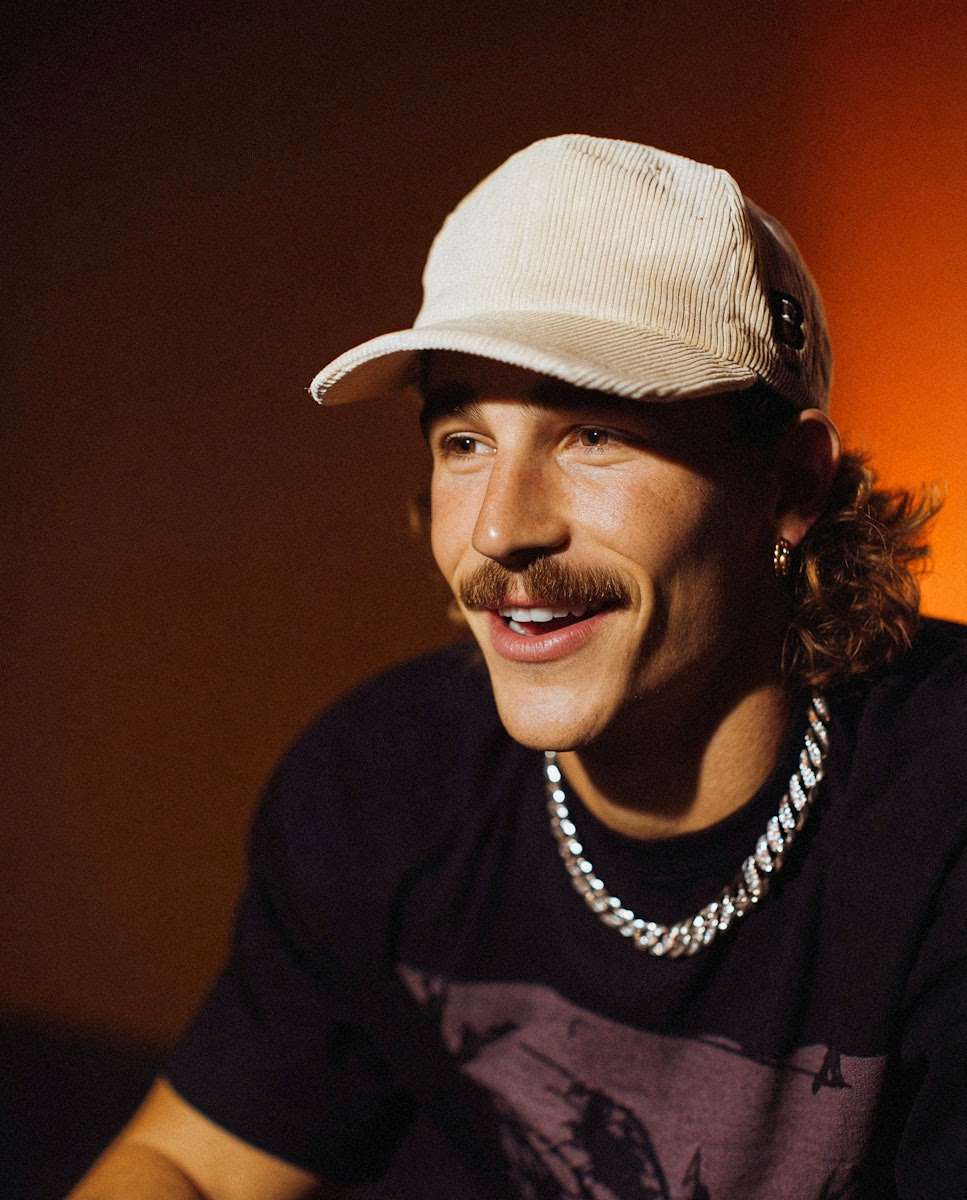 A man with a white cap and moustache against a red background, highlighting facial features and textures.