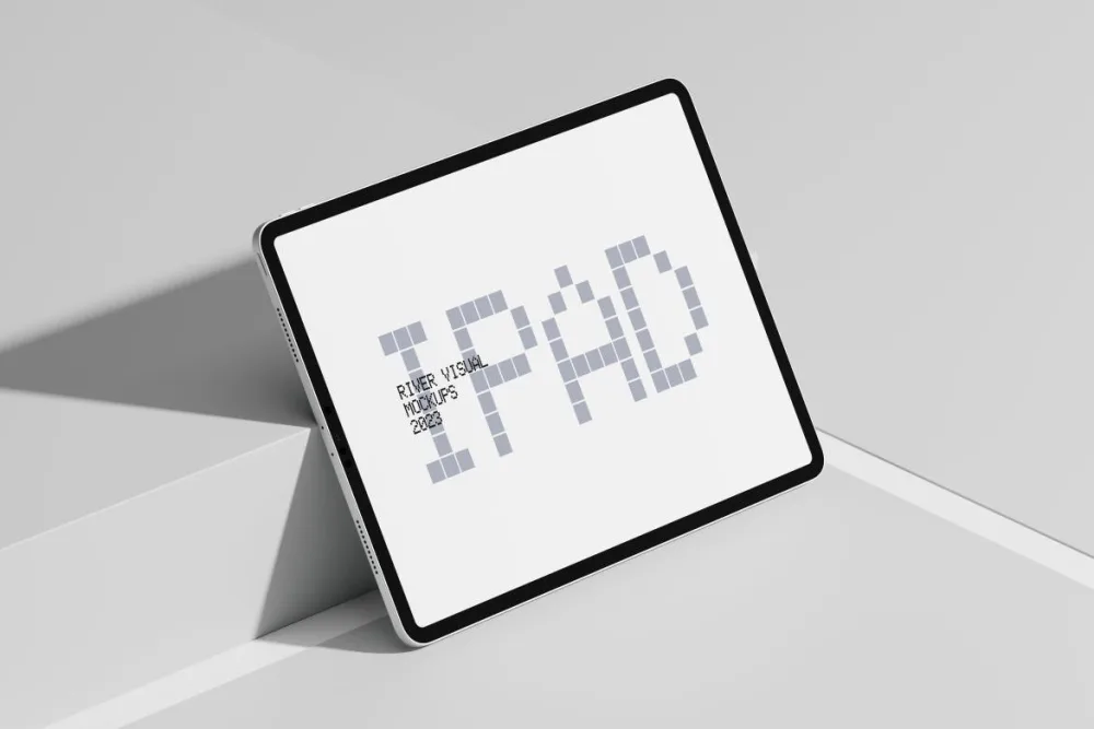 An iPad resting at an angle on a vibrant, geometric surface featuring red, blue, and green tones. The screen showcases a minimalist design, emphasizing the device's sleek and modern bezel.