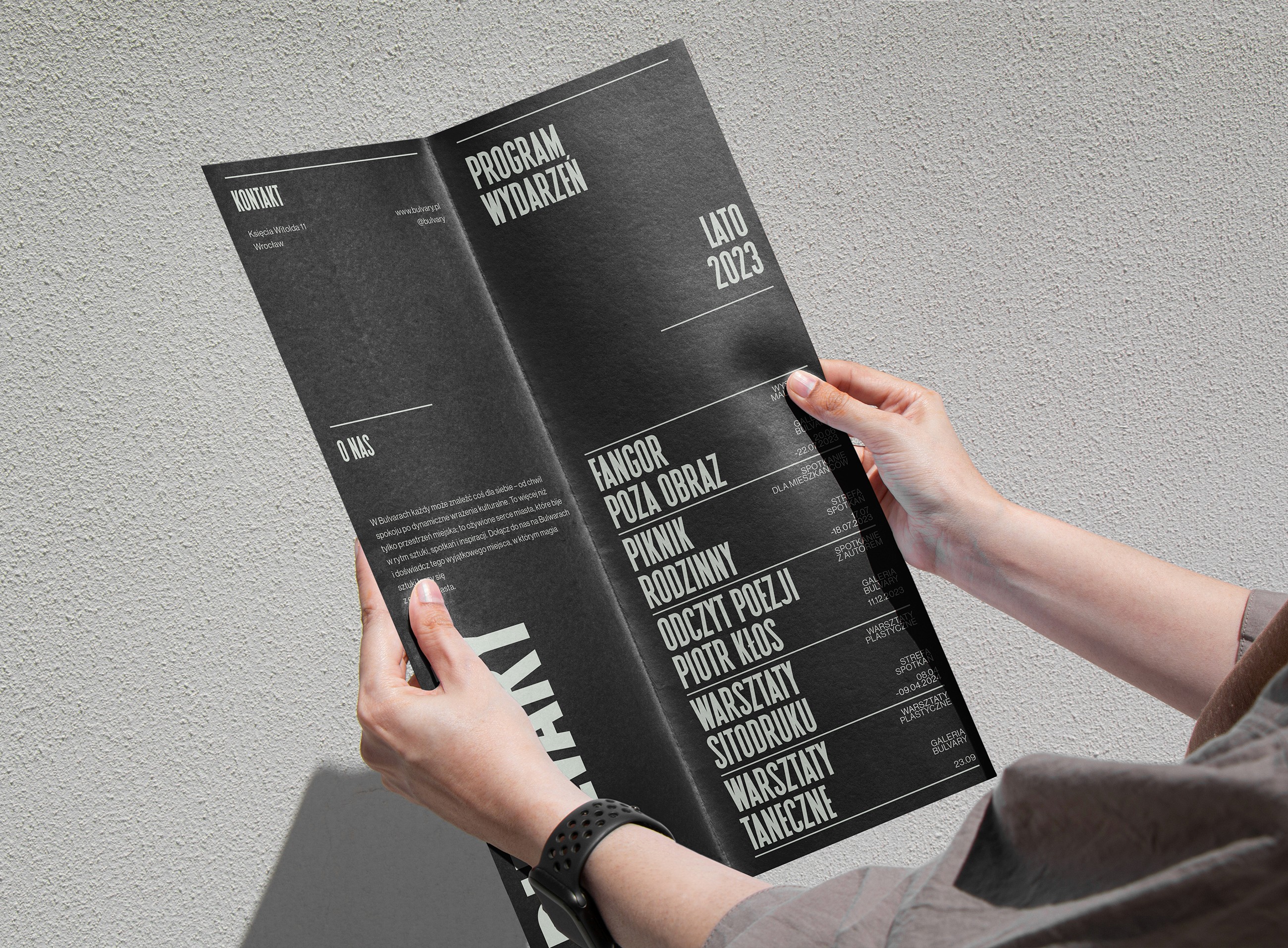 Hands holding a folded black Bulvary event programme leaflet for summer 2023, editorial design