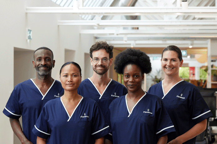 A group of four diverse nurses and healthcare workers in dark blue scrubs posing together in a healthcare setting