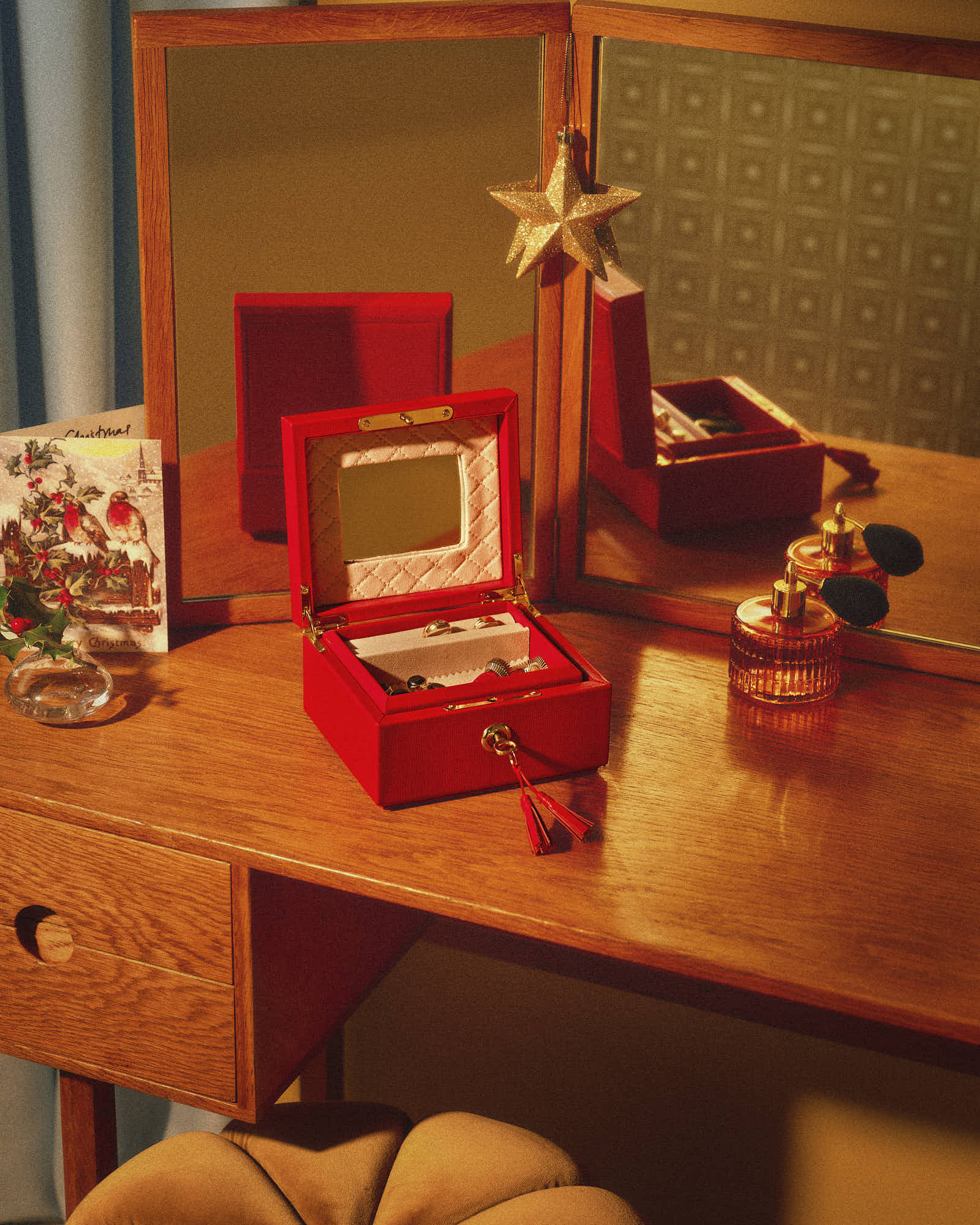 Vintage wooden vanity with mirror, red jewelry box, and elegant perfume bottles.