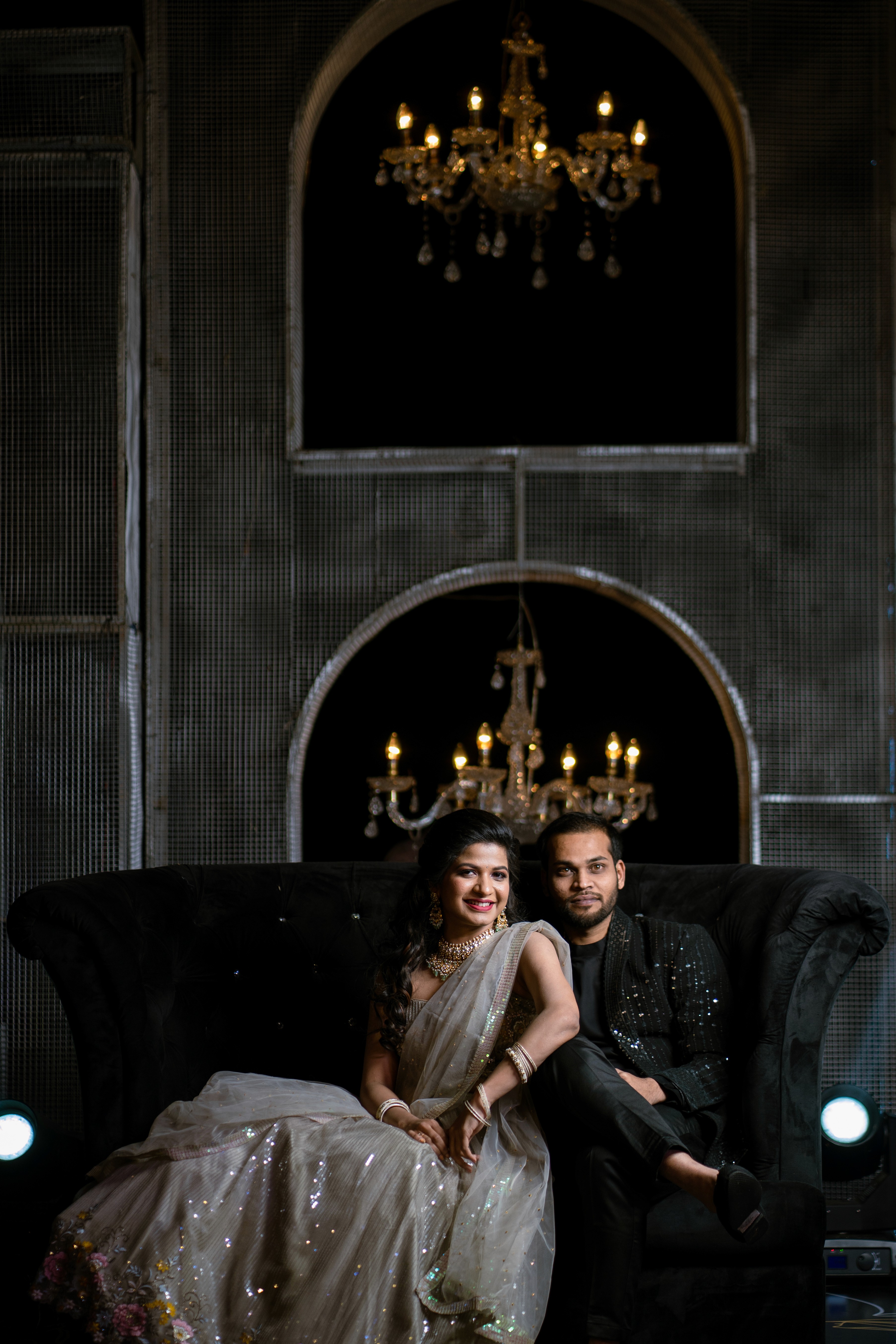 Mounika and Satya smiling warmly on a stylish sofa. Photo by Out of The Blues Fine Art Wedding Photography in Hyderabad.