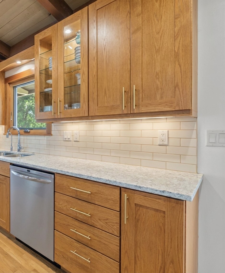 Refreshed shaker — same doors, lighter natural oak stain, no crown molding, updated hardware