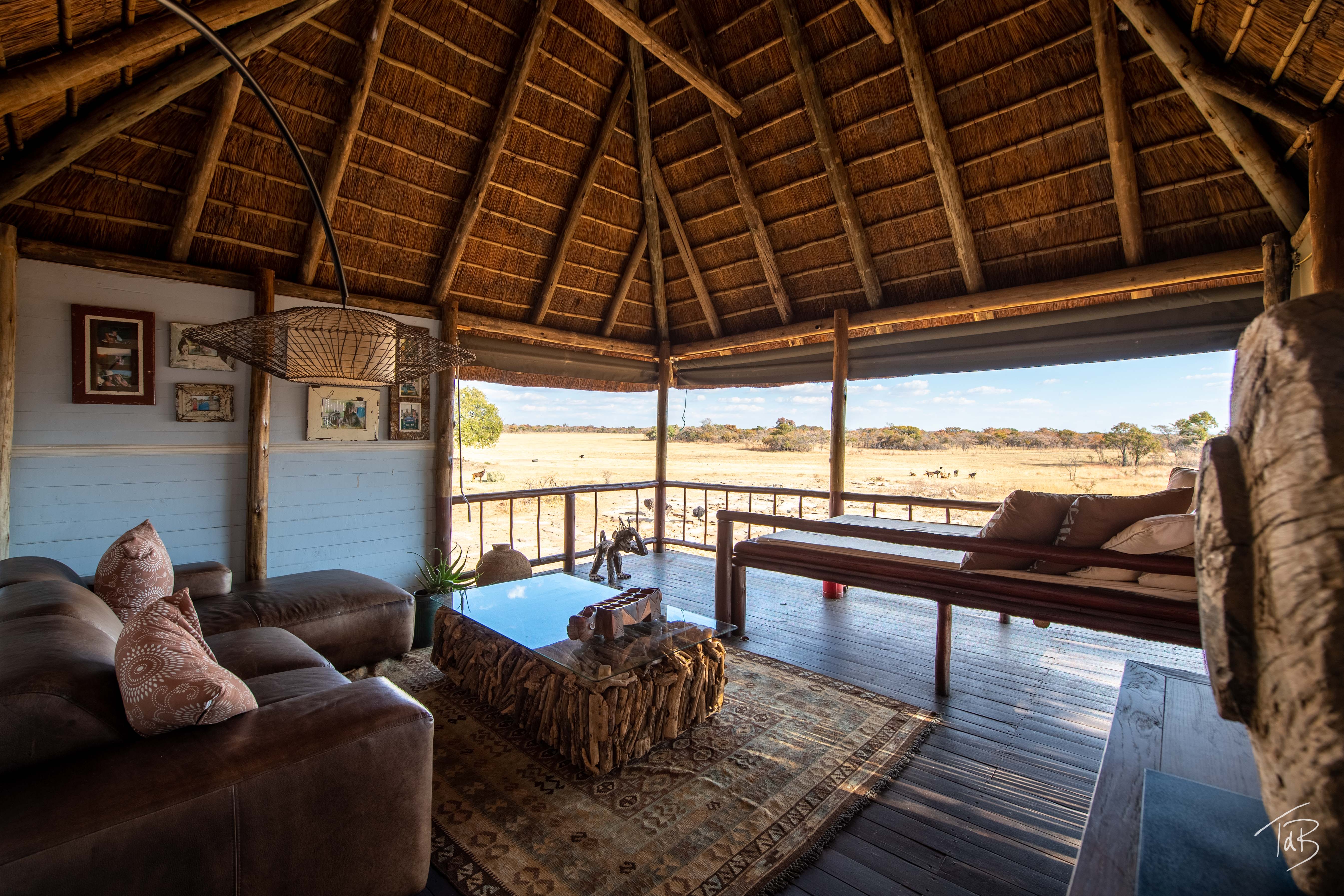 African Explorer, Waterberg, Sydafrika – Savannah Lodge utkiksplats med soffa och loungemiljö, med utsikt över en gyllene savann fylld av vilda djur.