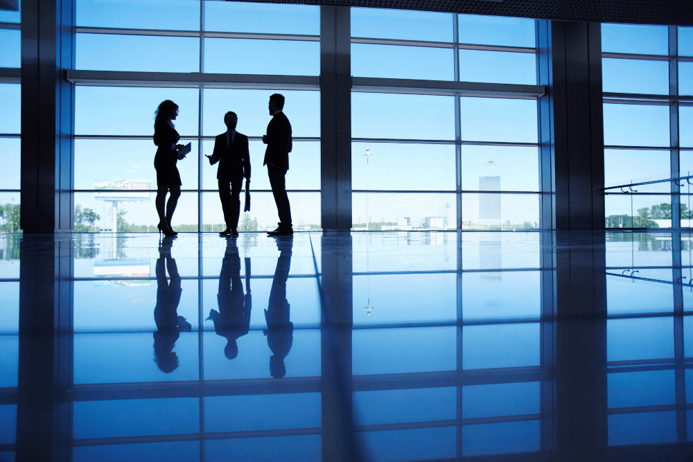 Franchise owner managers talking by a high window, with blue vibe.
