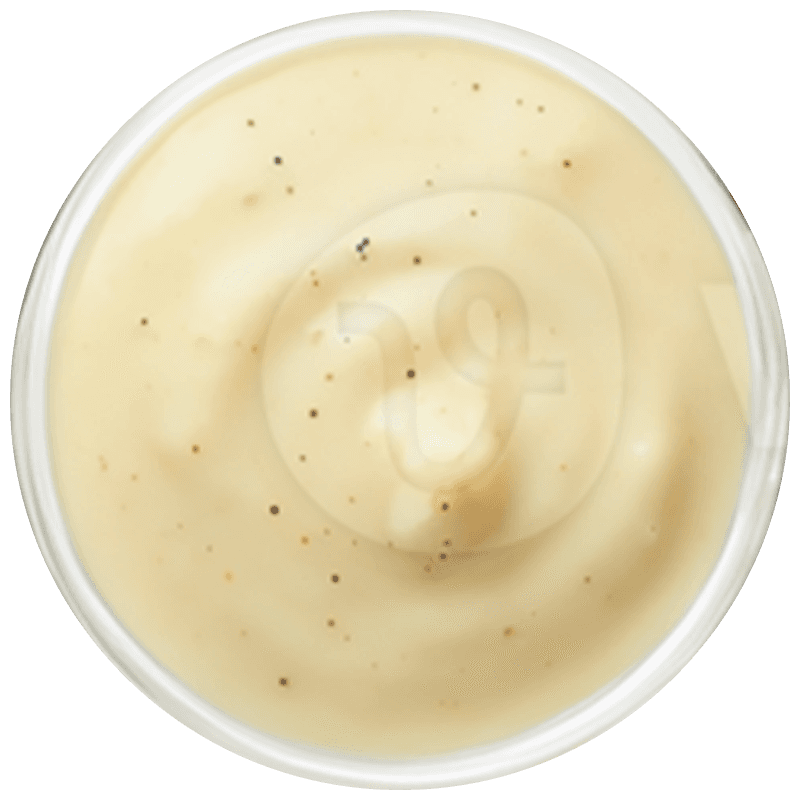 A bright, modern dining room featuring a long light wood table set with several matching wooden chairs and white cushions, illuminated by natural light streaming through large windows overlooking a lush green and sunlit yard.