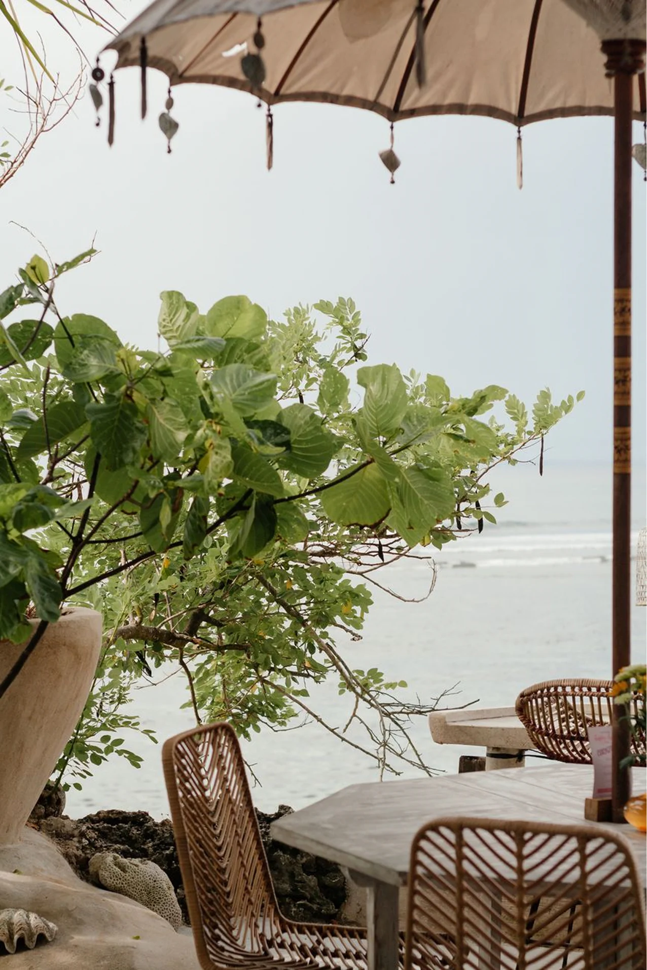 Outdoor resort dining setup on a wooden terrace beside a green lawn and palm trees.