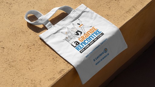 Tote bag en tissu blanc de l'enseigne E.Leclerc pour une opération de recrutement appelée "La Grande Rencontre", posé sur une surface en béton clair.