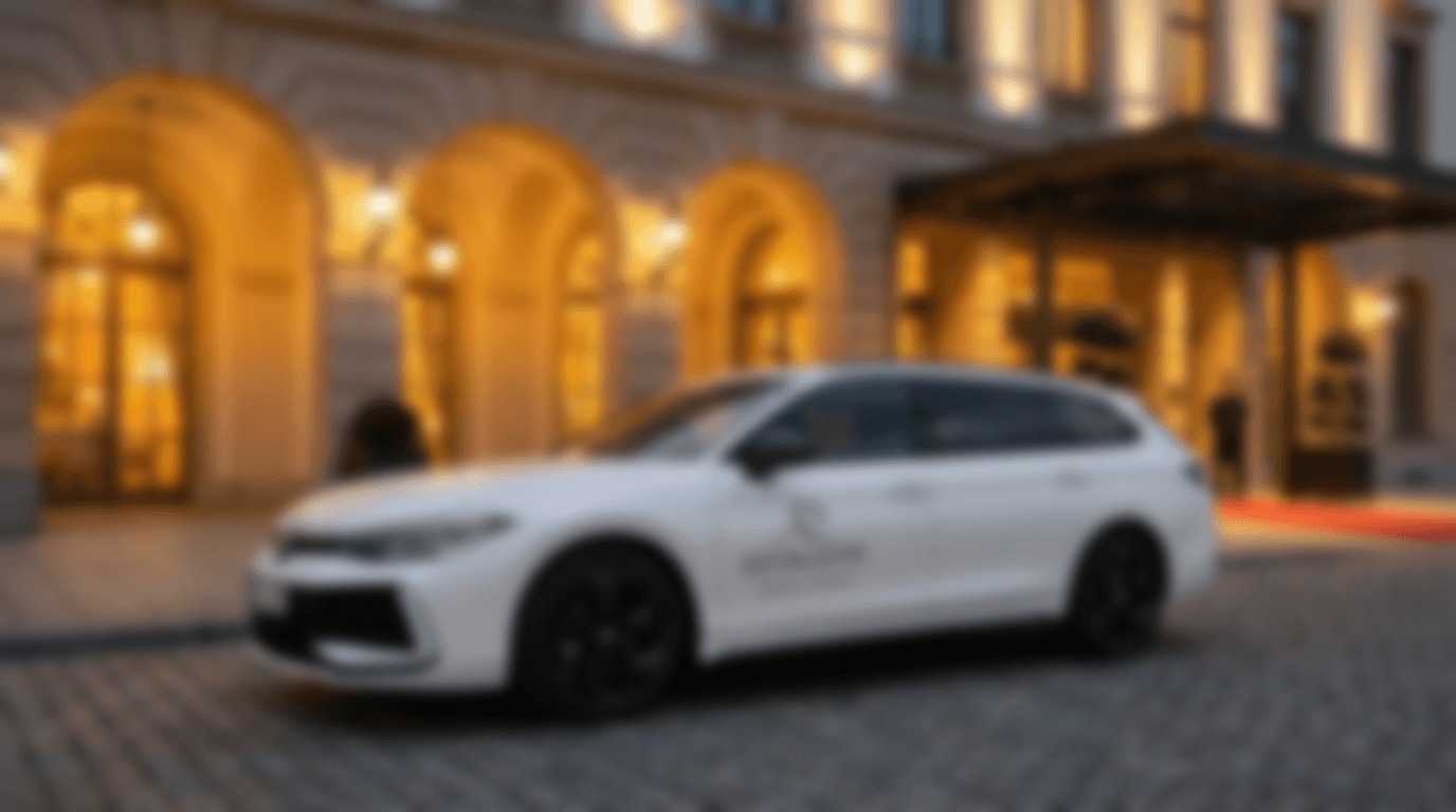 Weißer Volkswagen passat parkt vor einem warm beleuchtetem luxus Hotel. Roter teppich im hintergrund