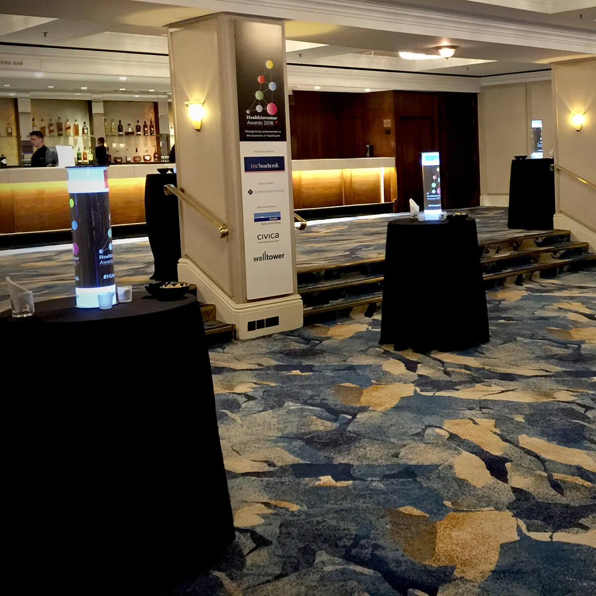 Bar area at an event with banners and glowing table promo tubes