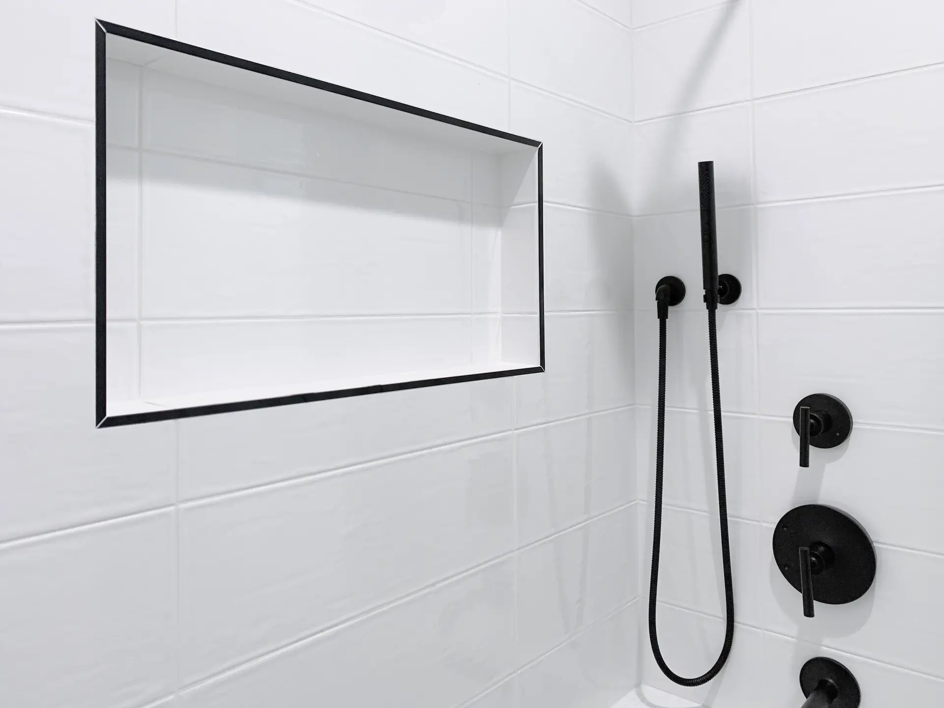 Closeup of the kids' bathroom shower niche, featuring black Schluter trim and textured wall tile, a perfect blend of functionality and style. Photo by Todd Huge.