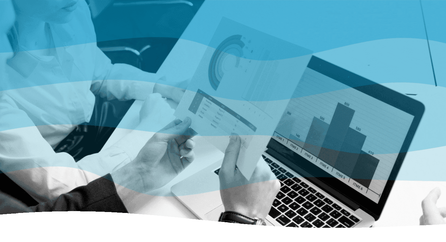 Two people analyzing charts and graphs on a laptop and printed documents in an office setting, indicating a  meeting focused on data analysis.