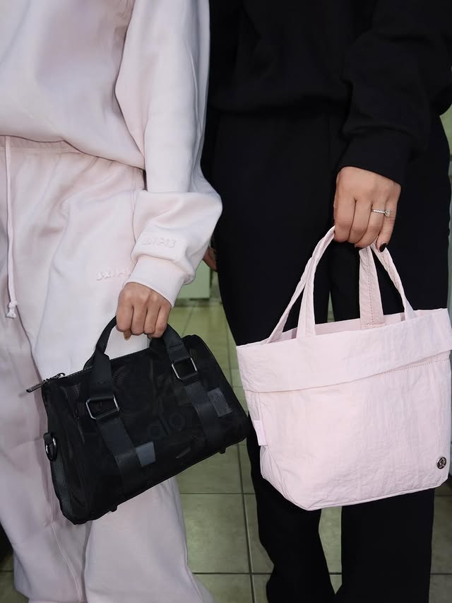A man with curly hair in a brown jacket leans on a stair railing